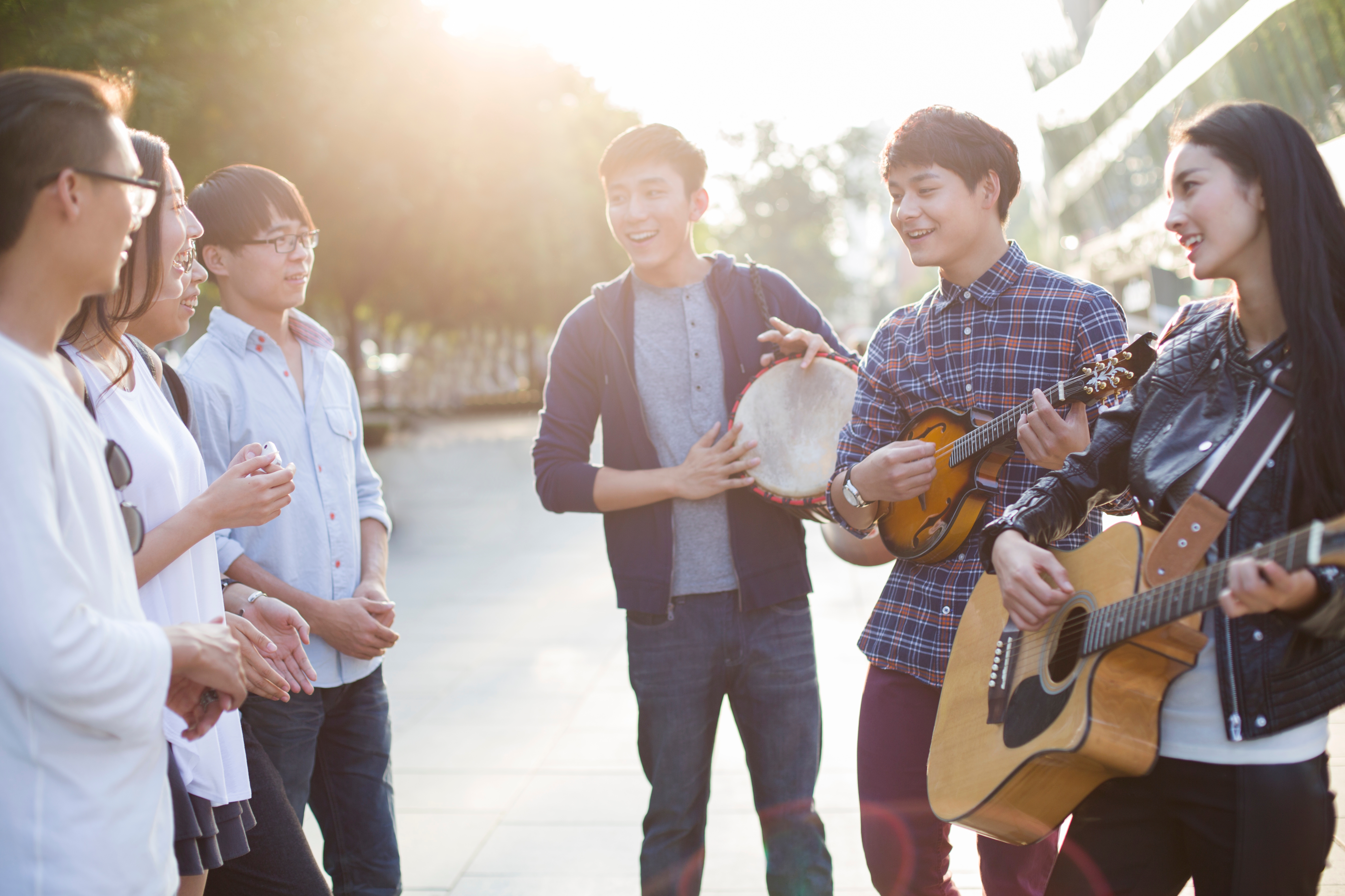 A group of asian young adult friends in the city playing music together