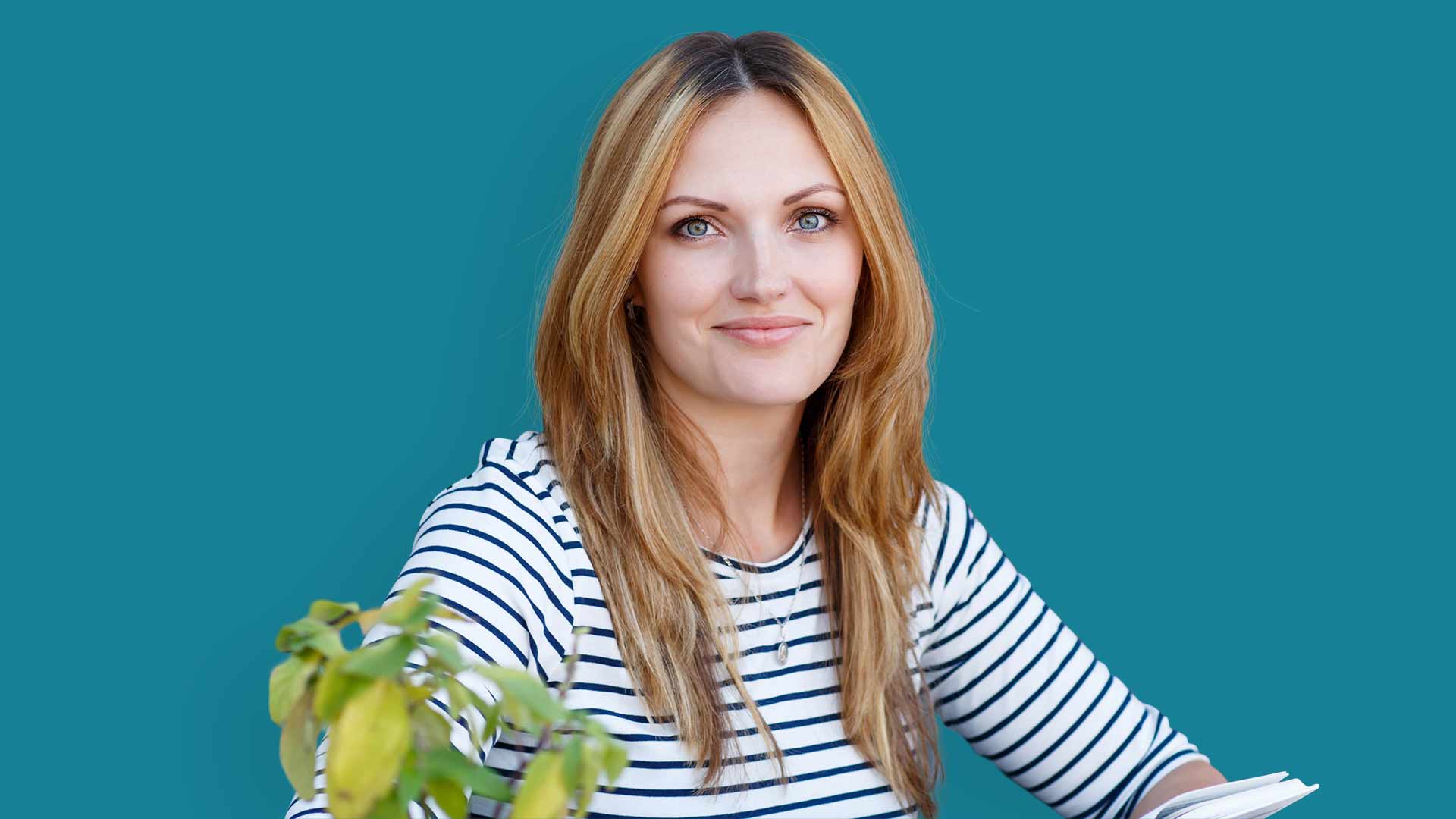 Young woman holding a book with her hands. A woman in a blue and white striped shirt, holding a book with her hands.