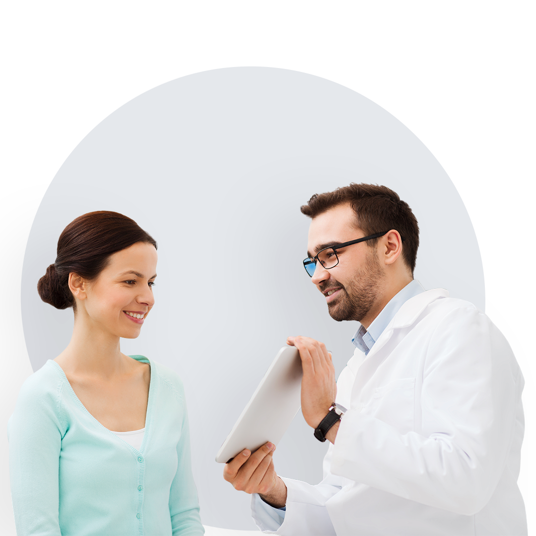 Jeune femme souriante qui se voit montrer une tablette par un docteur.