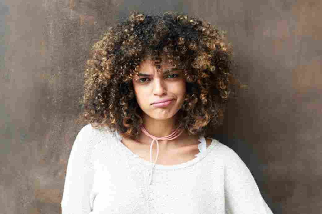 Frowning young woman with curly hair looking straight ahead 
