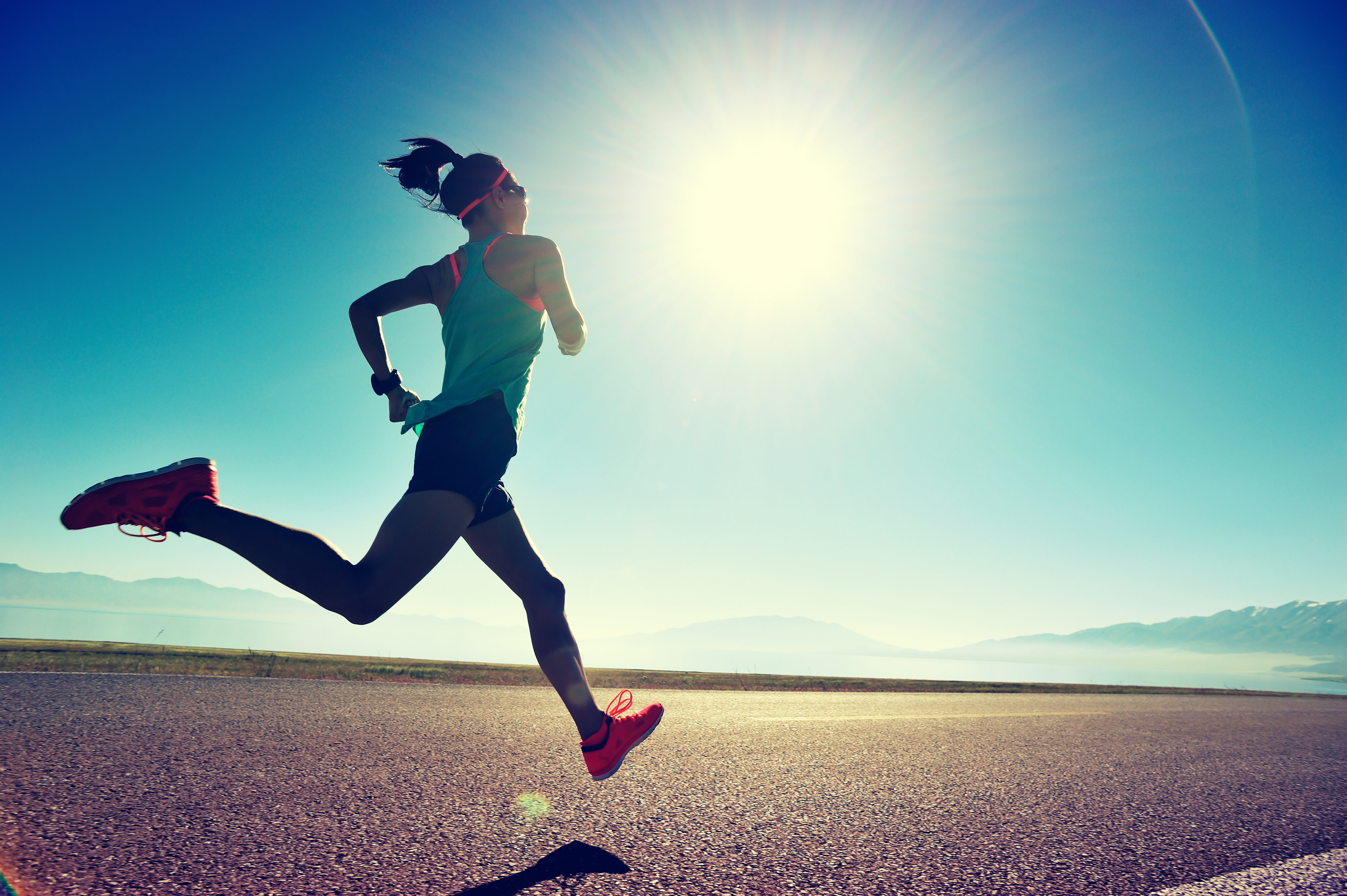 A woman running freely with sunglasses under the sun at the freeway