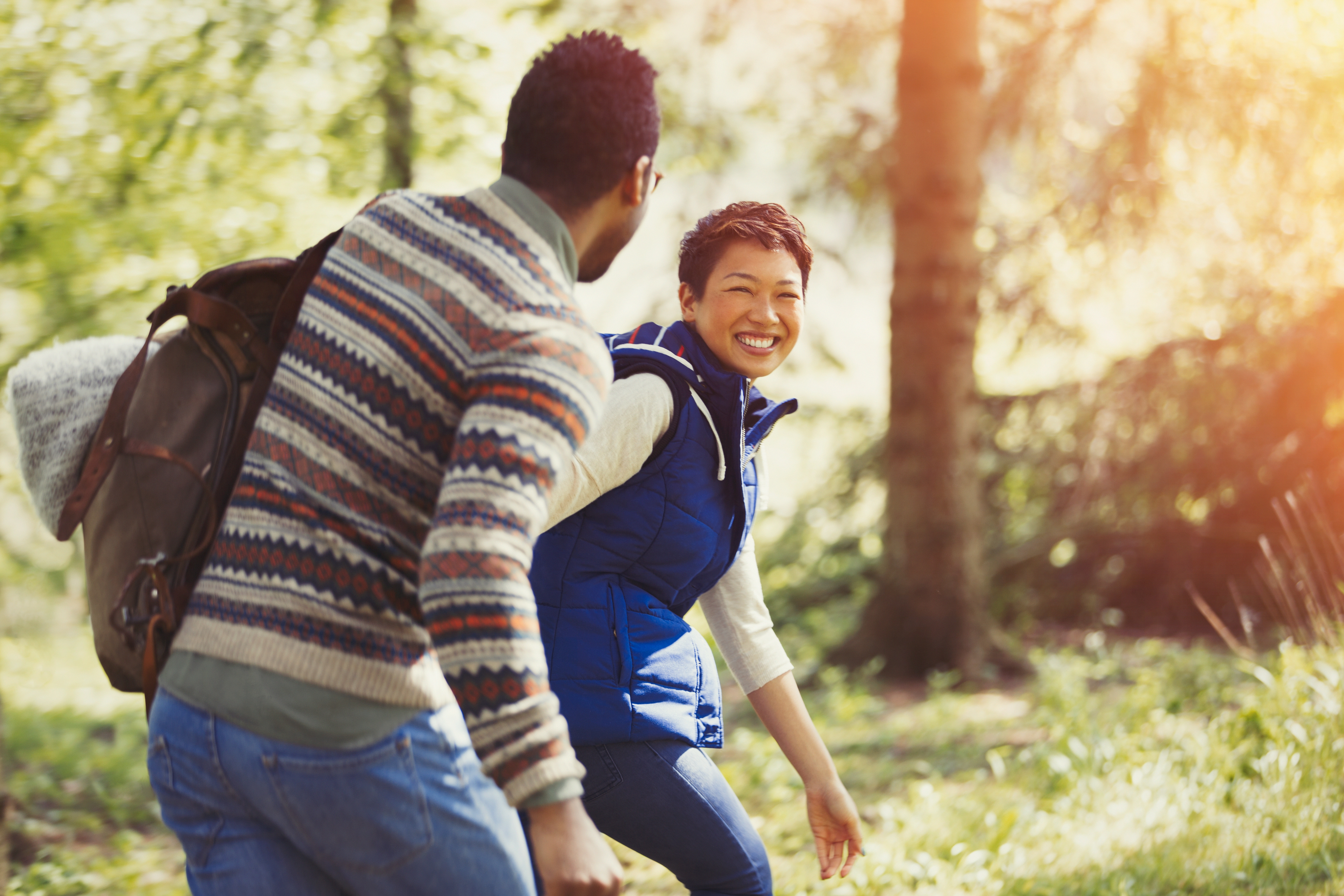 Two young adults smiling at each other while hiking in the forest