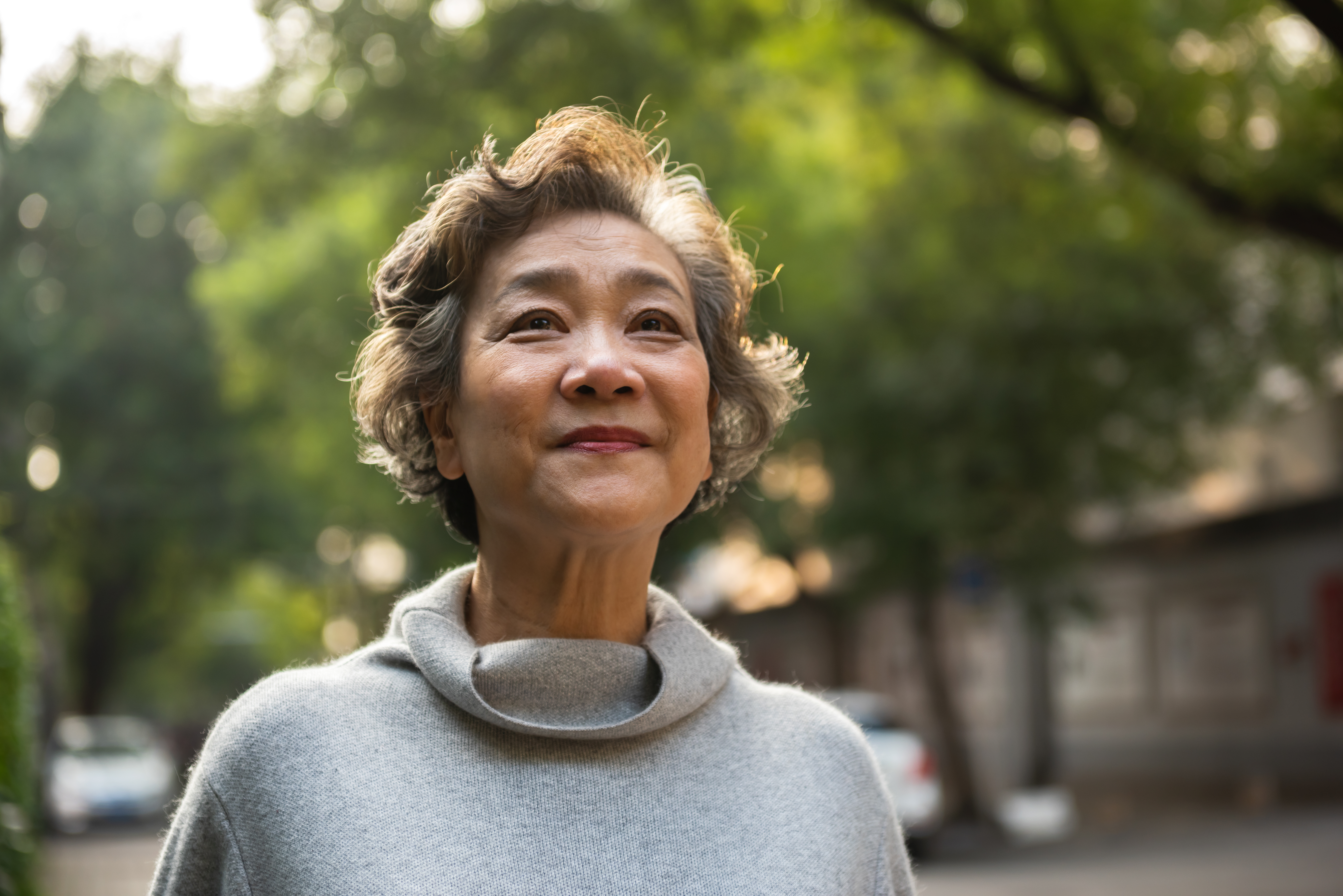 Middle aged Asian woman smiling outside.