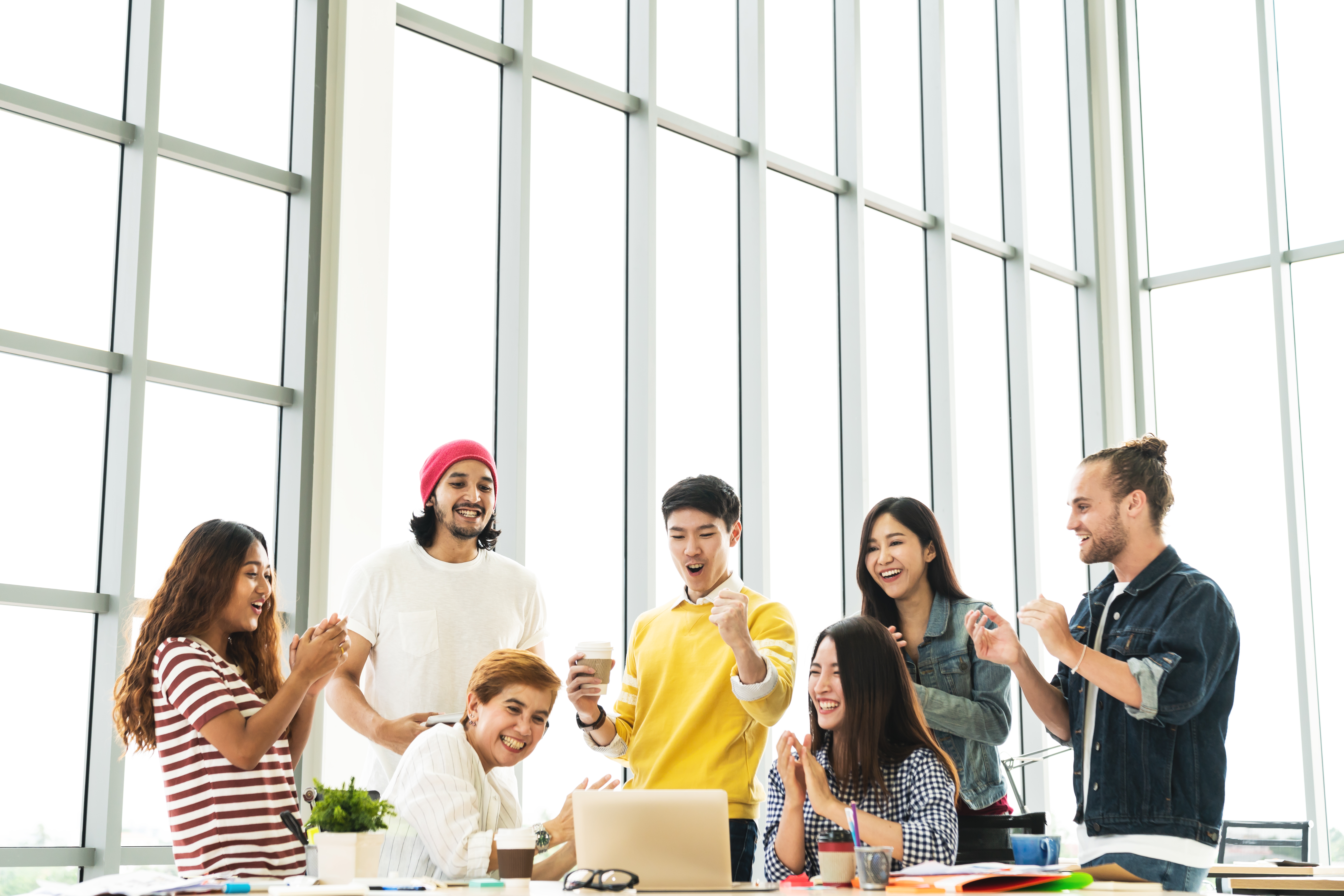 Four women and Three men looking happy and all smiling in a workplace.