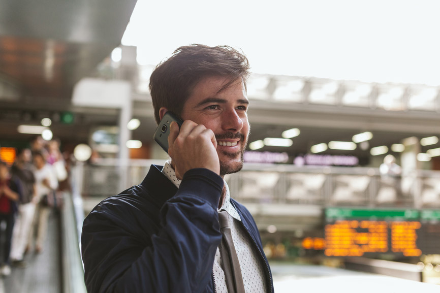 Usmívající se muž s plnovousem volá mobilním telefonem