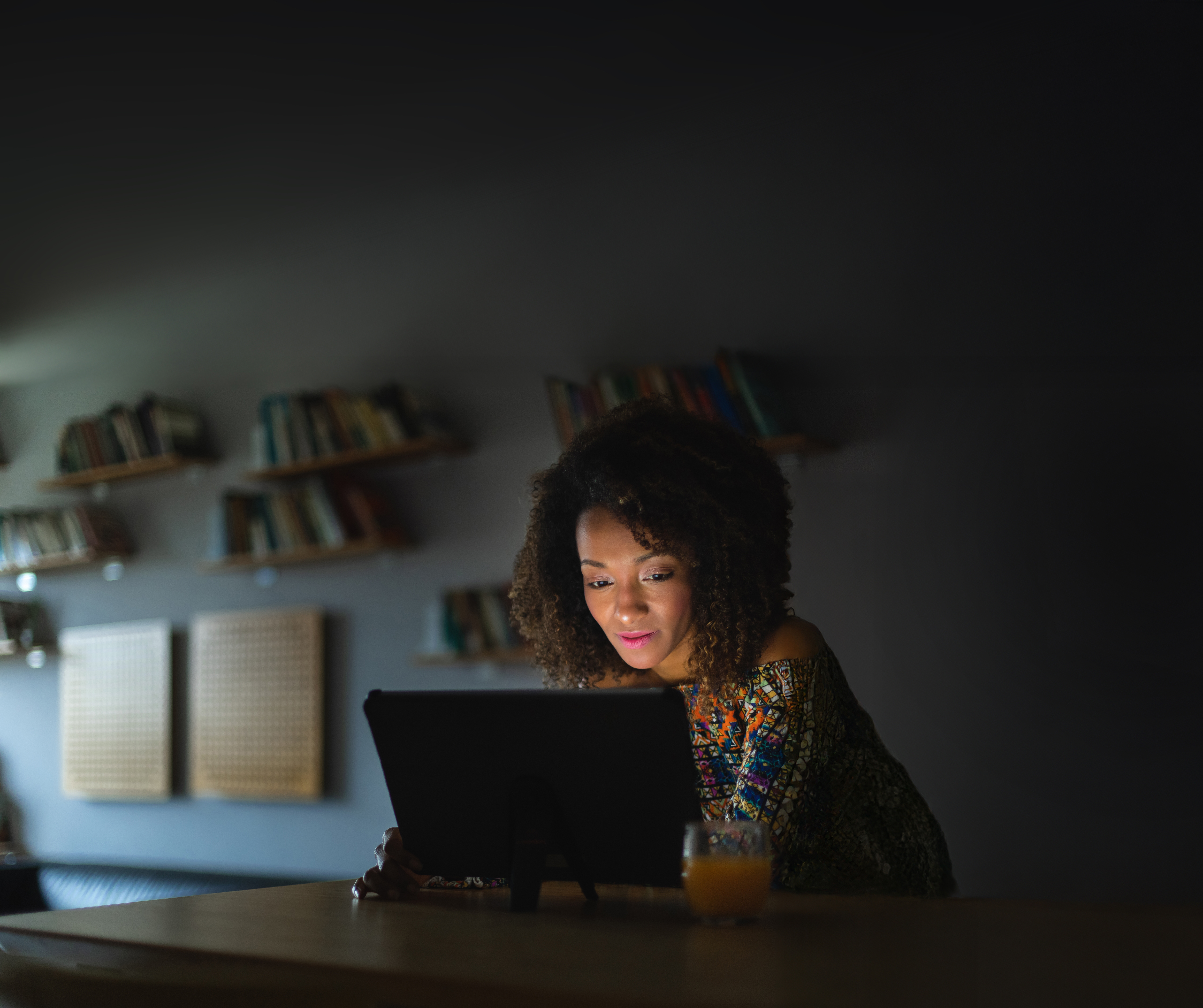 A woman looking at her laptop screen in a dimly lit room A woman looking at her laptop screen in a dimly lit room