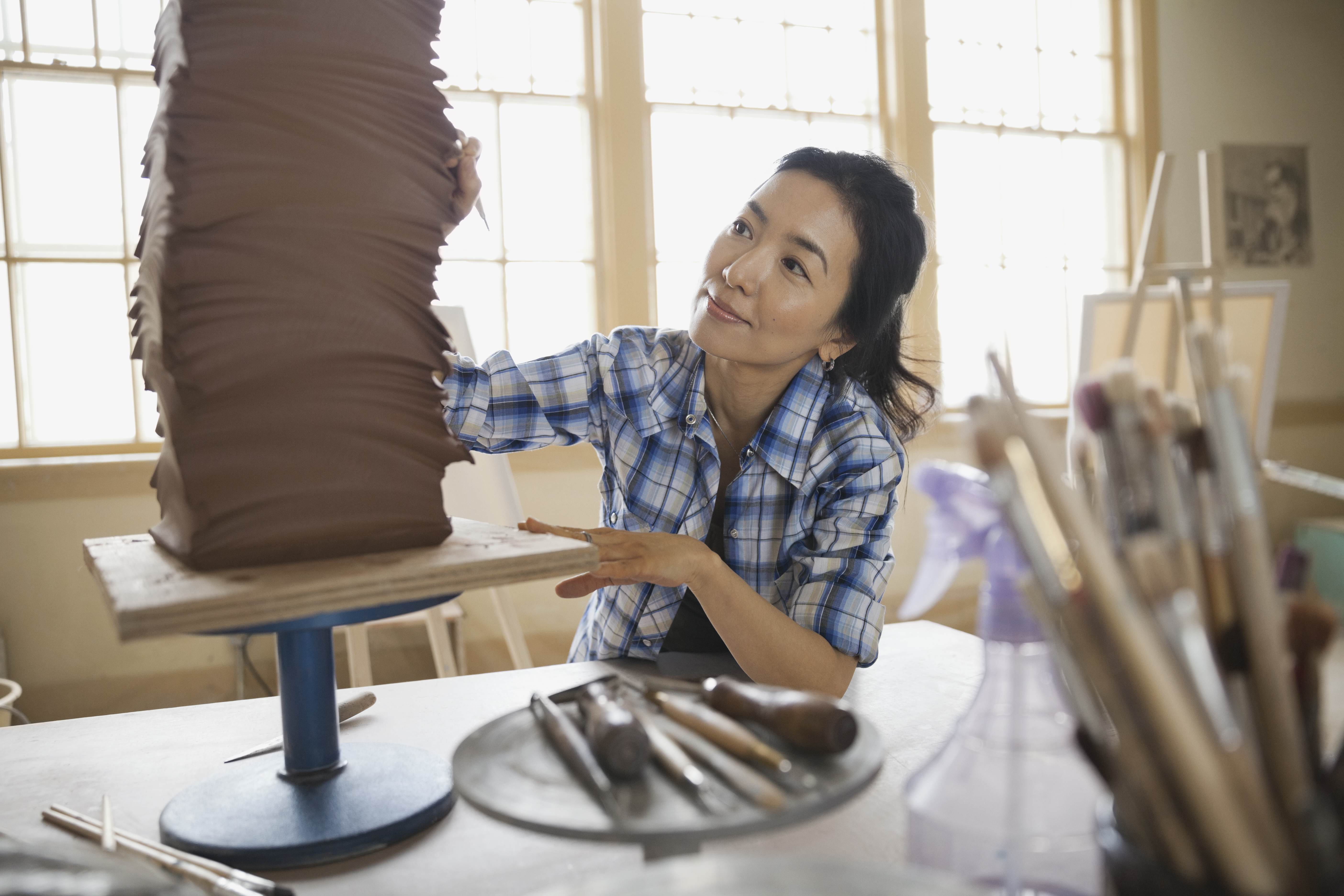 An Asian woman working out her crafts in the studio.