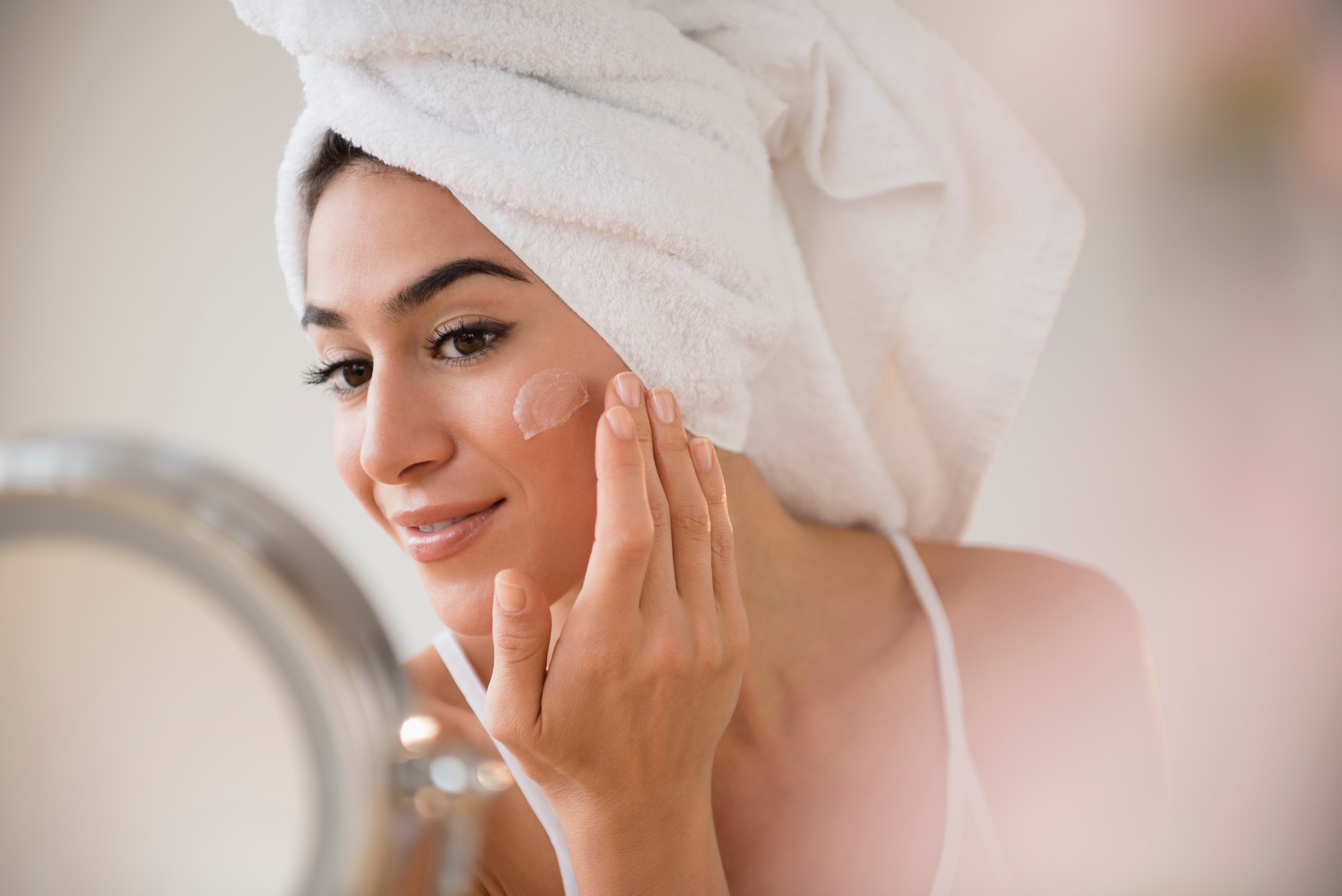 Asian woman with towel wrapped around the hair getting ready with contact lenses