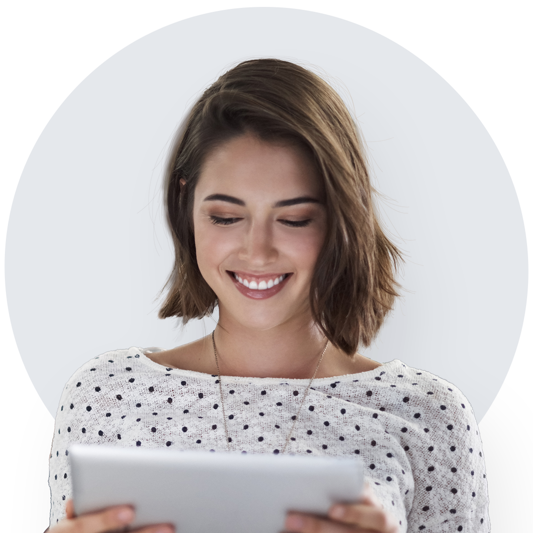 Jeune femme souriante aux cheveux courts et bien coiffés vêtue d’une blouse à pois qui regarde une tablette