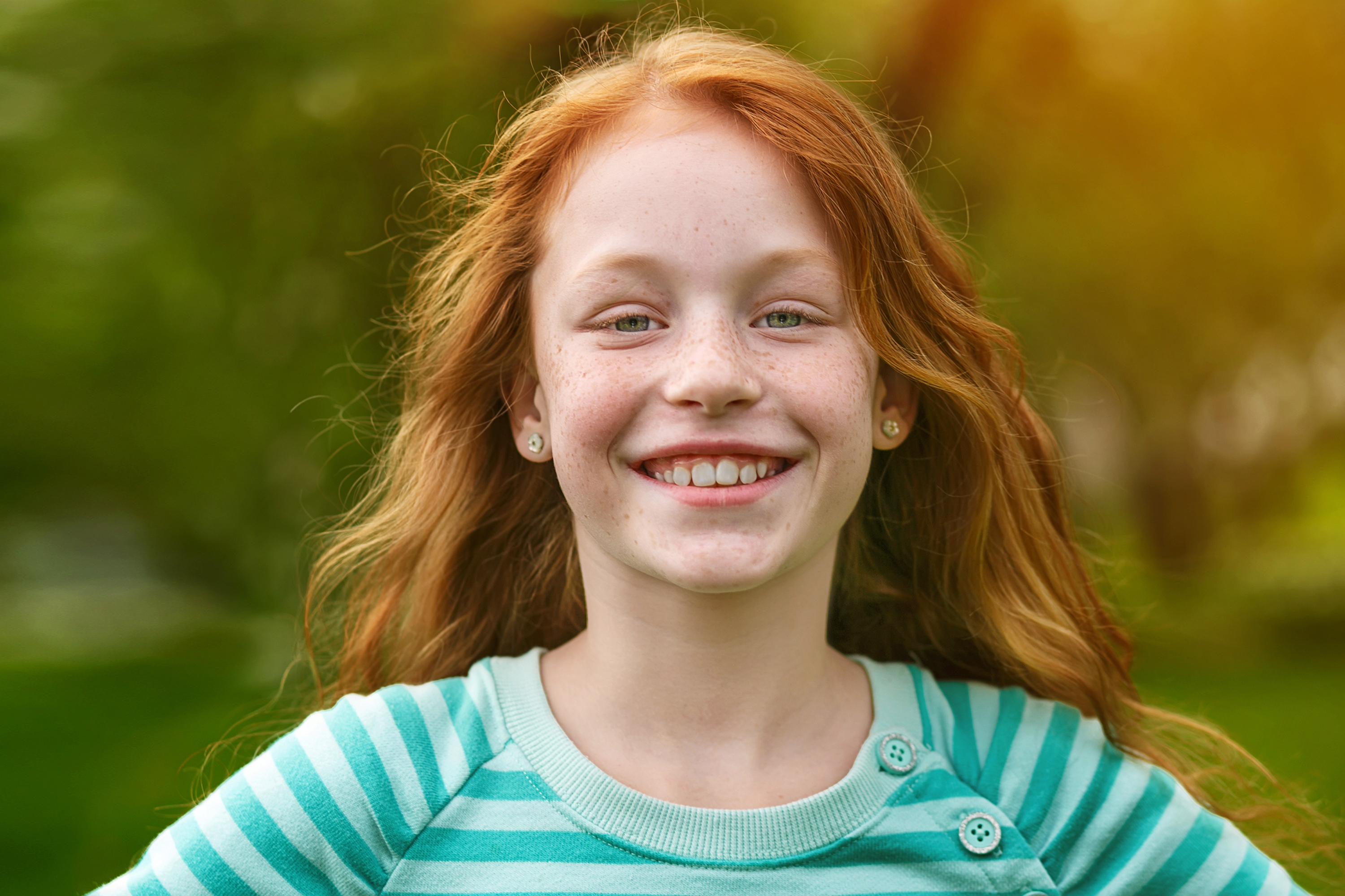 Девочка в полосатой футболке улыбается в камеру