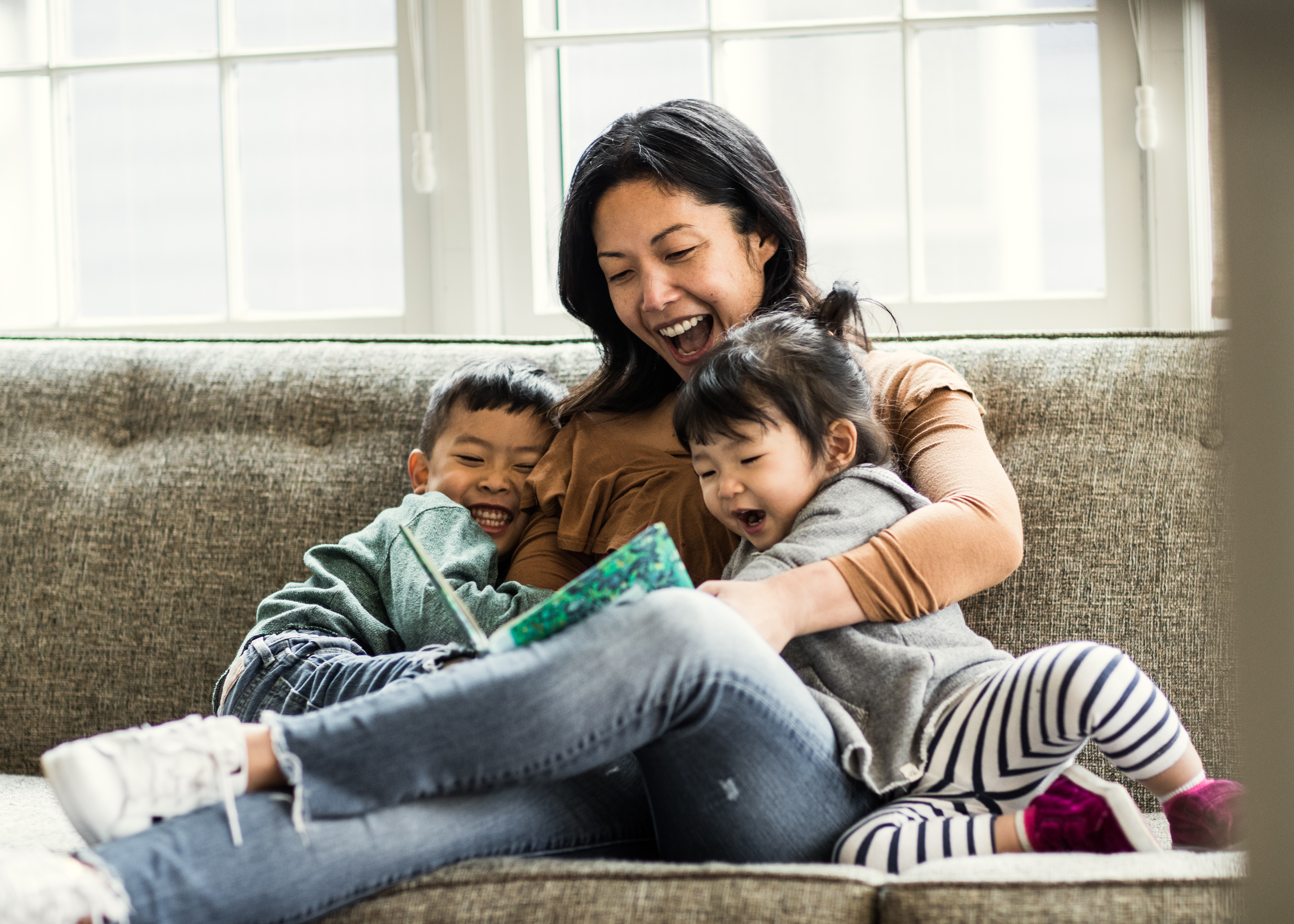 Smiling woman enjoying her time with kids by reading the storybook.