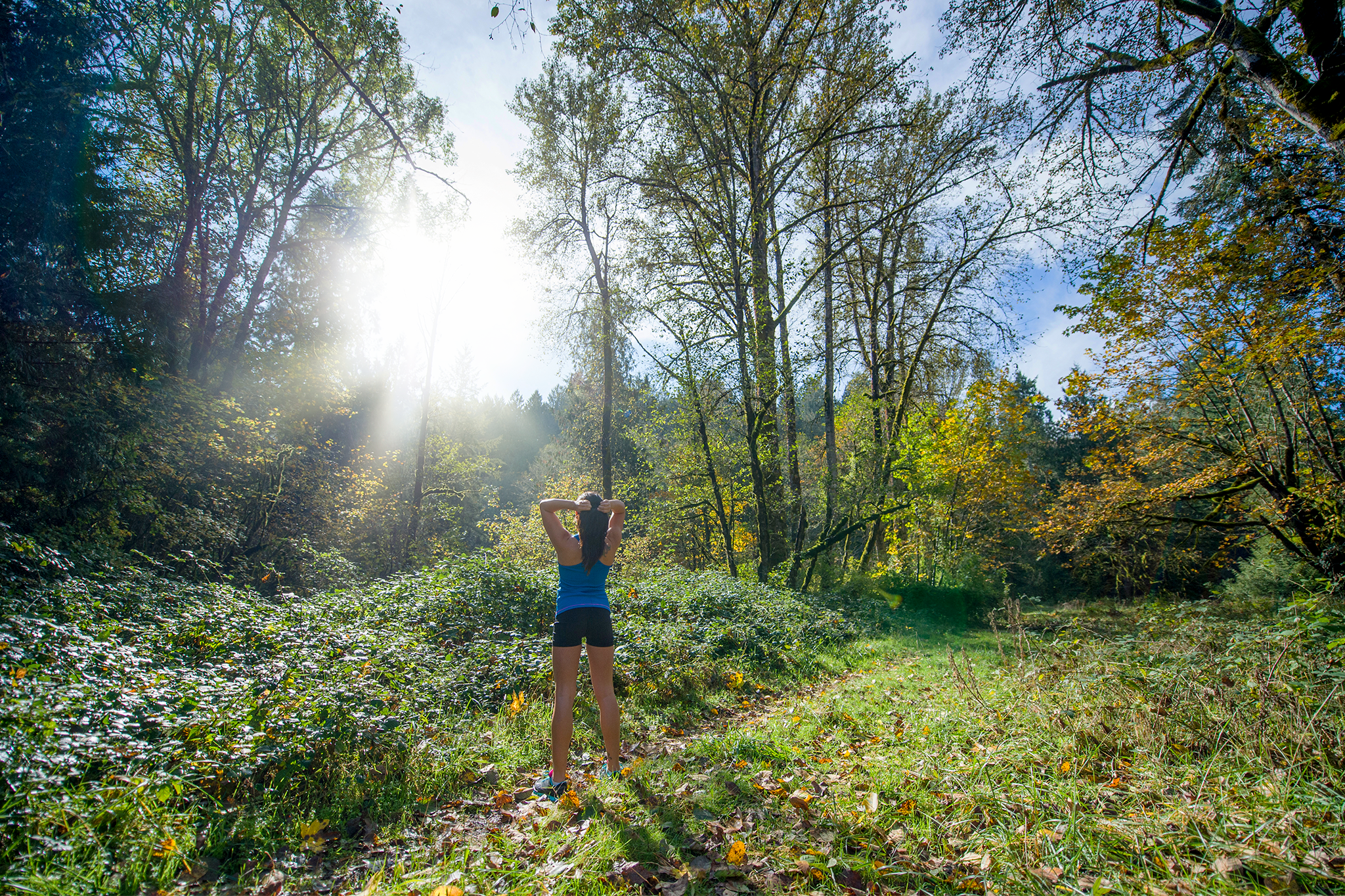 A woman hiking in the forest with sunlight beaming through the trees, but blurry.