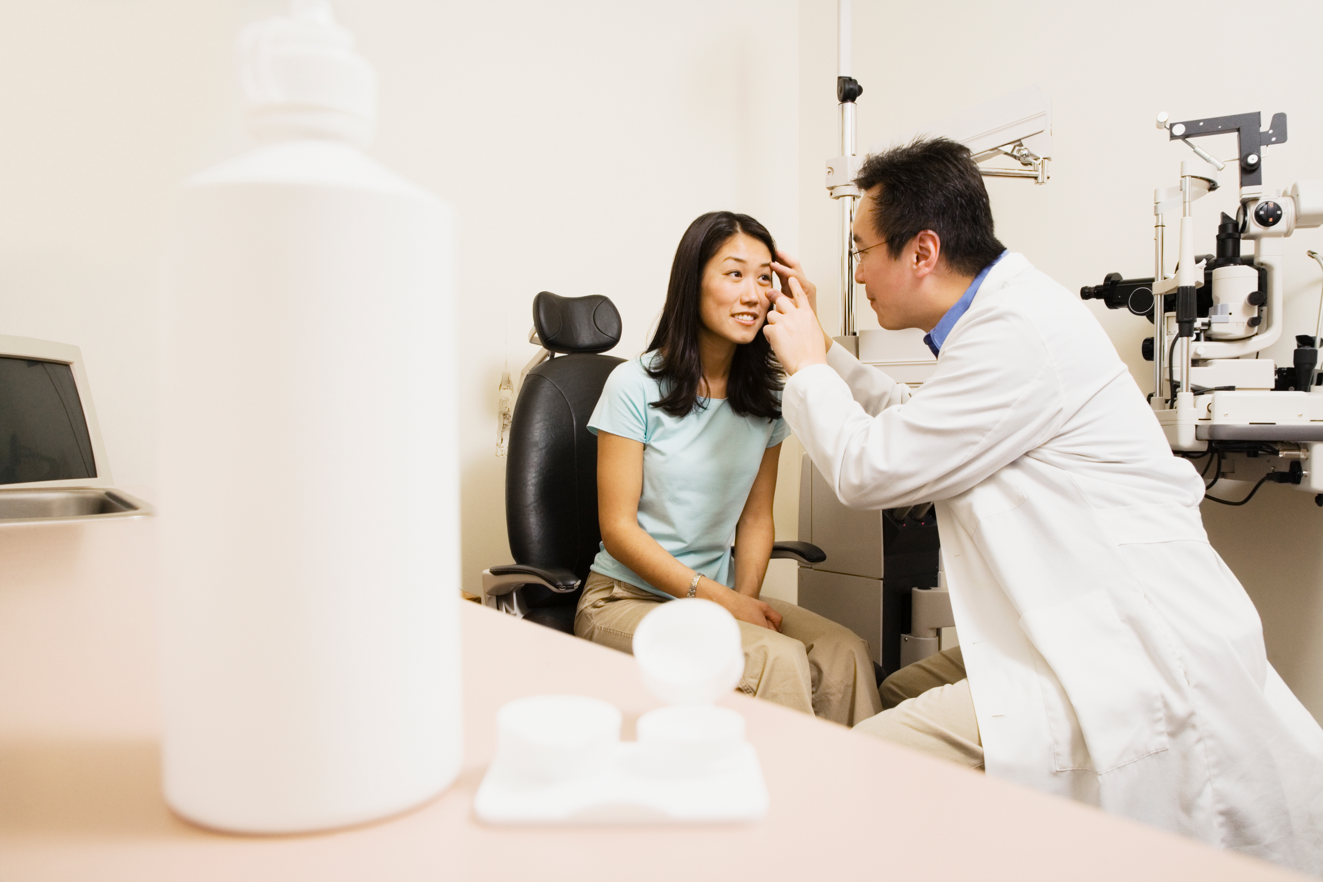 Asian woman with warm smile when optometrist examining her eye