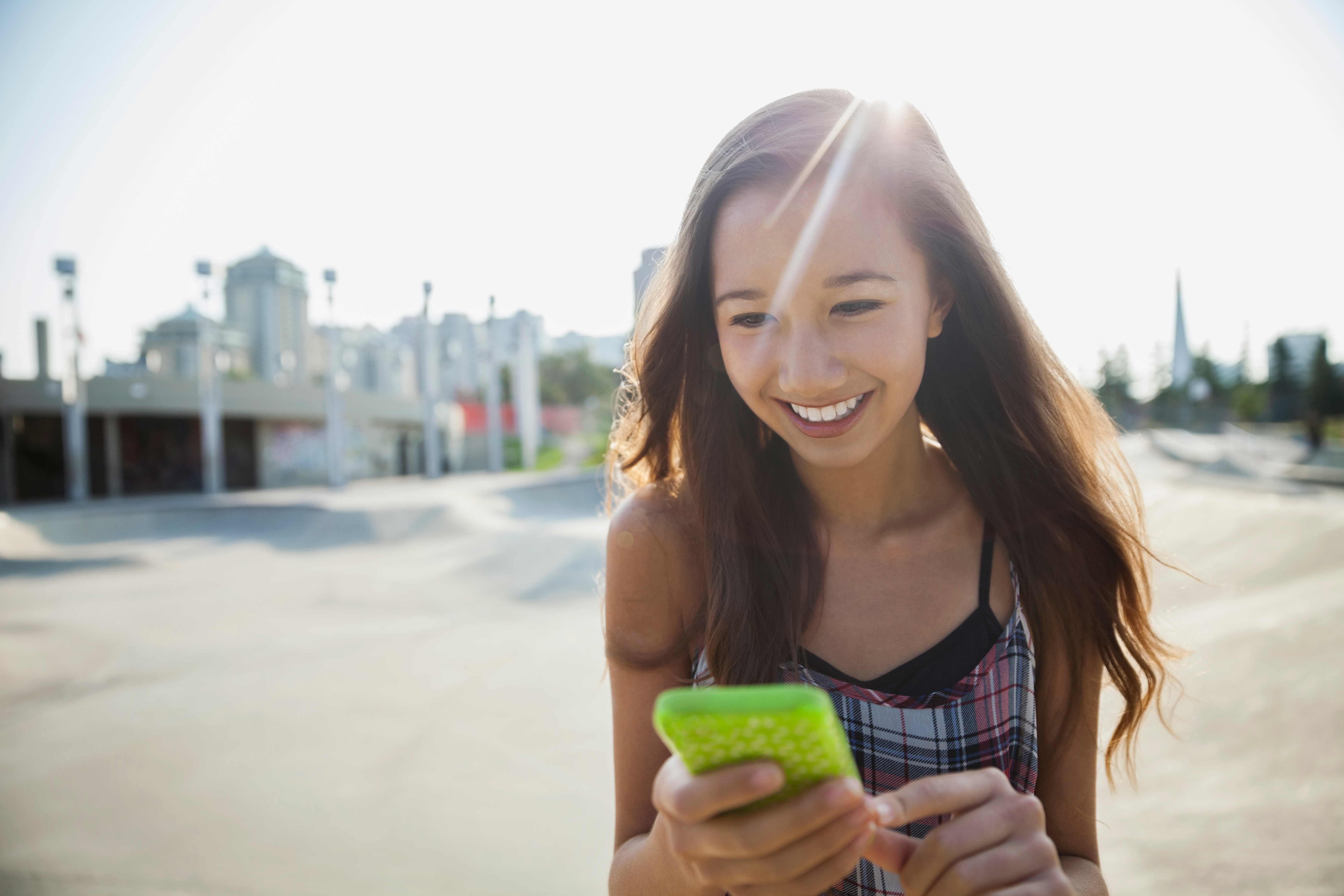 A smiling young girl on her green mobile phone.
