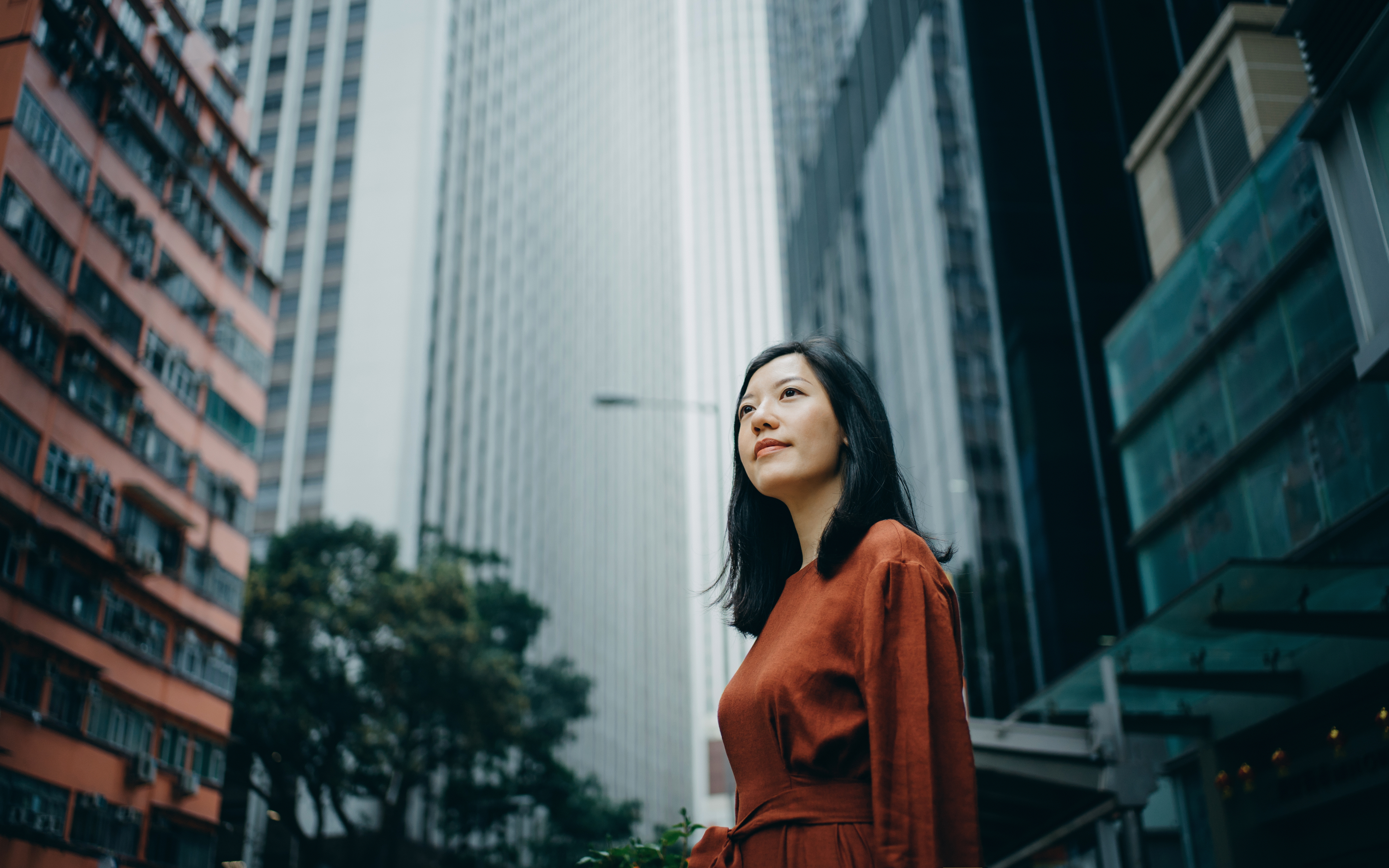 A young long haired girl looking over her shoulder and gazing at the environment on the street