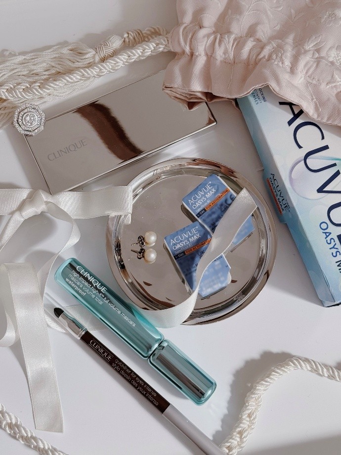 An image of a variety of clinique makeup on a white table with ACUVUE contact lenses on a small silver tray Clinique and ACUVUE collab