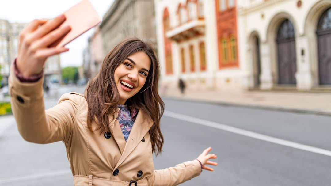 Young woman holding her cell phone up to take a selfie