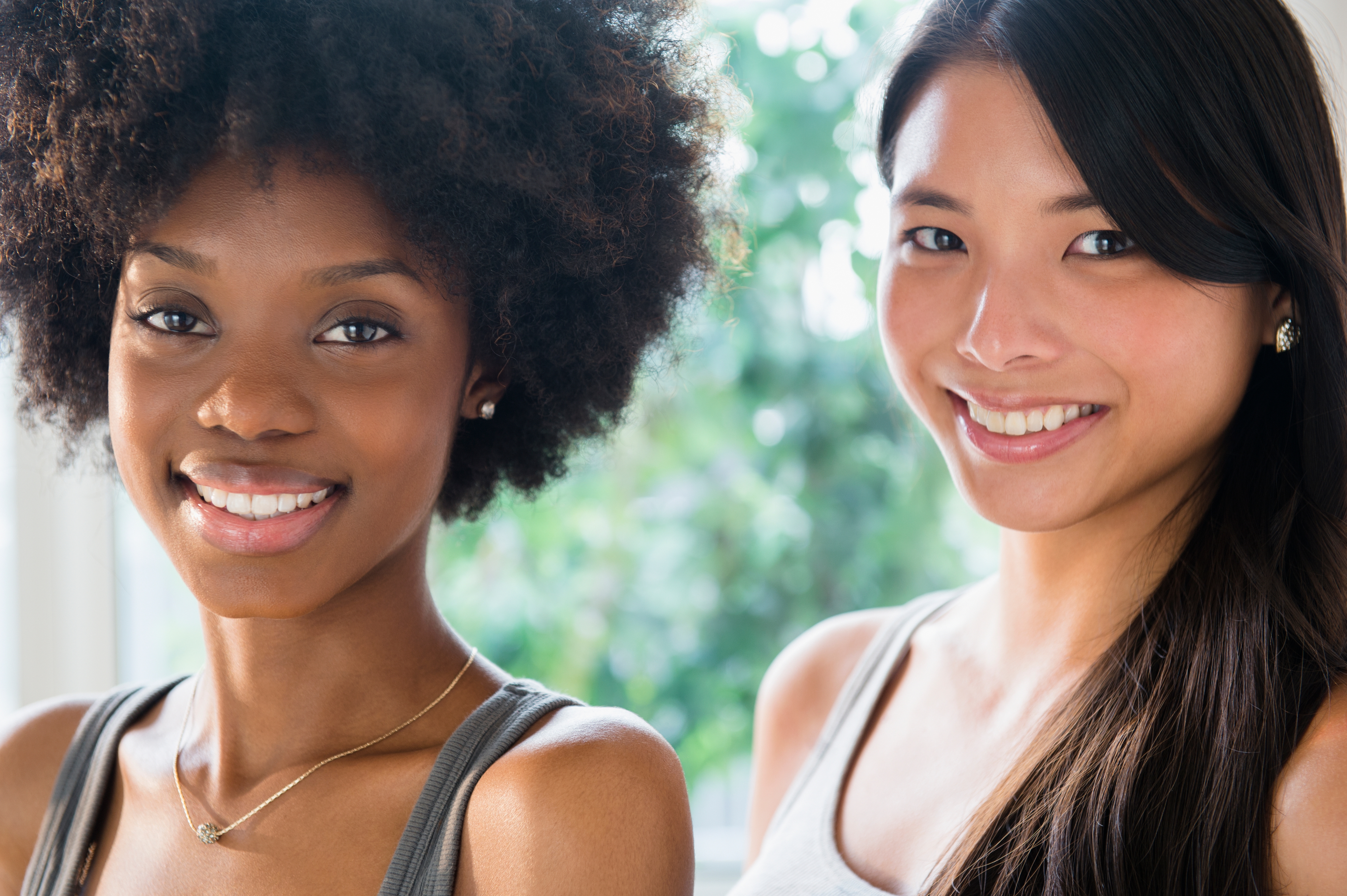 Two young women smiling facing forward.