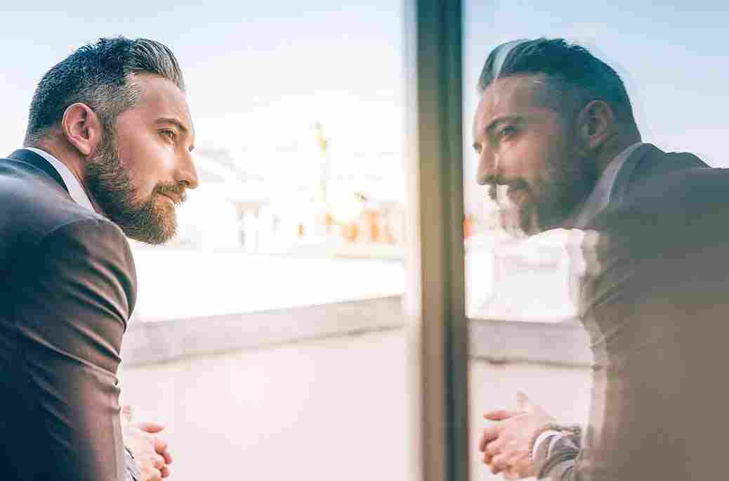 Mature man looking at his reflection in a window.