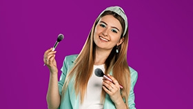 Alicia, a professional make-up artist and wearer of ACUVUE Contact Lenses holds two make-up brushes.