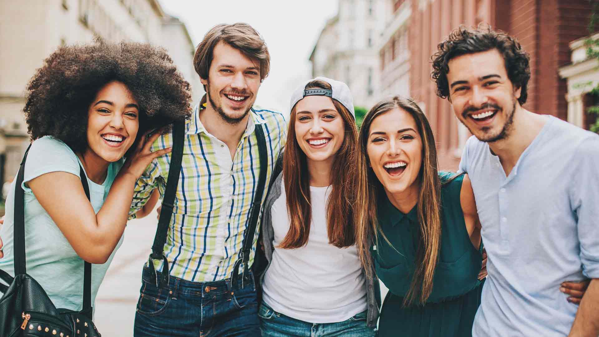 Três mulheres e dois homens, todos sorrindo, tirando uma foto 