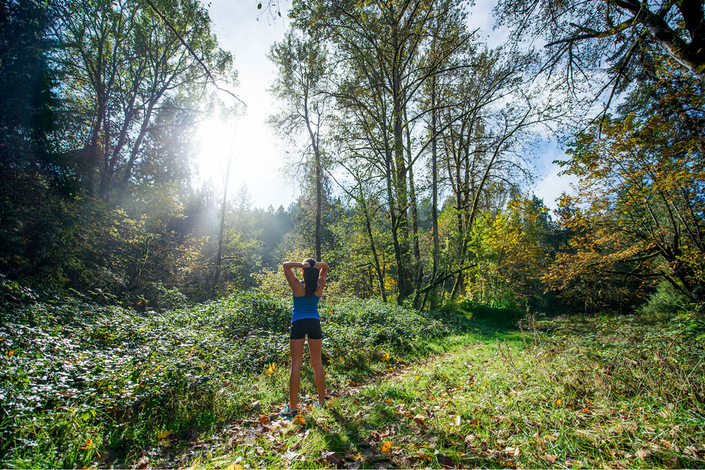 Ormanda yürüyüş yapan ve güneşe selam veren kadın