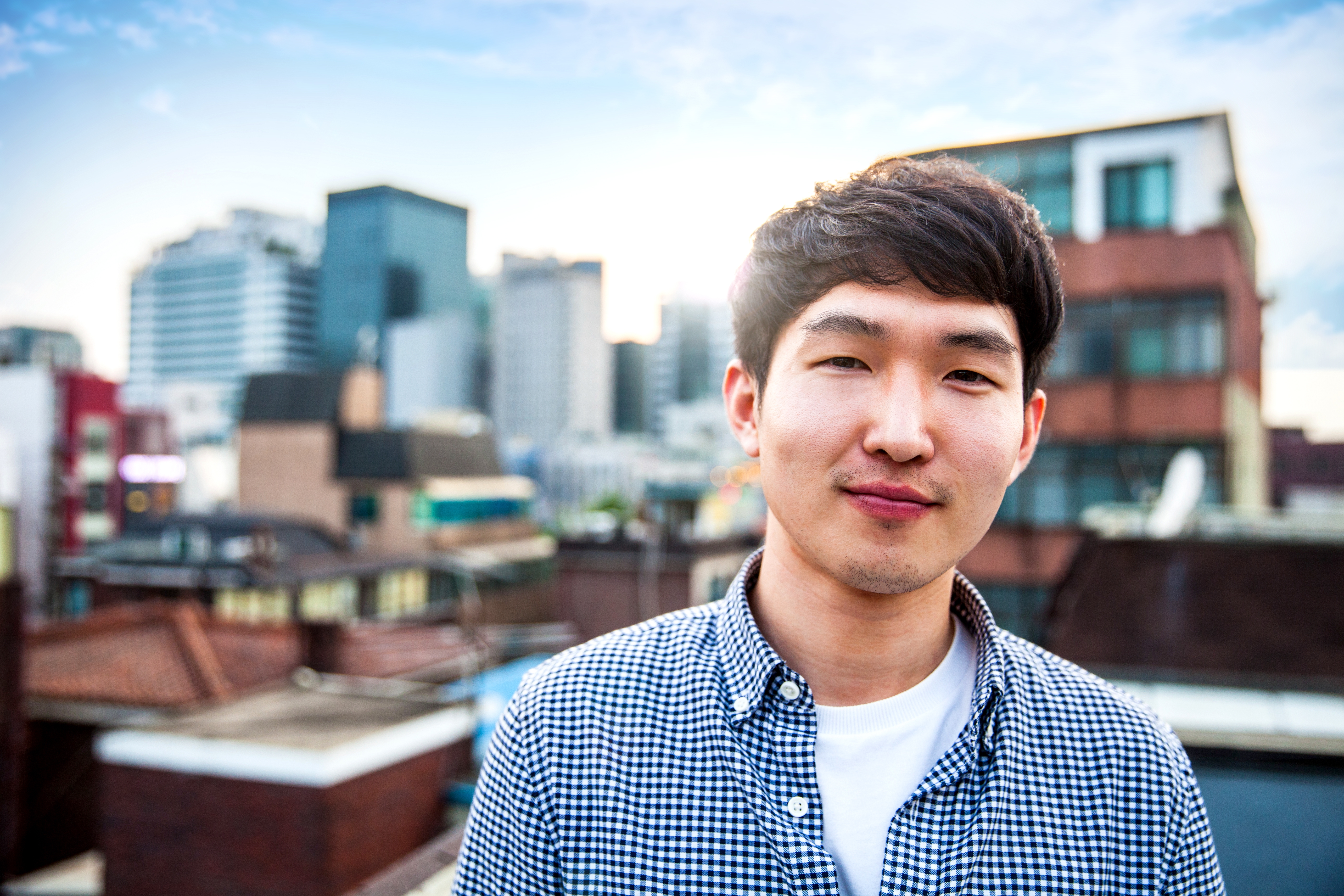 Asian young man with a warm smile looking straight ahead with sunshine rise in the background