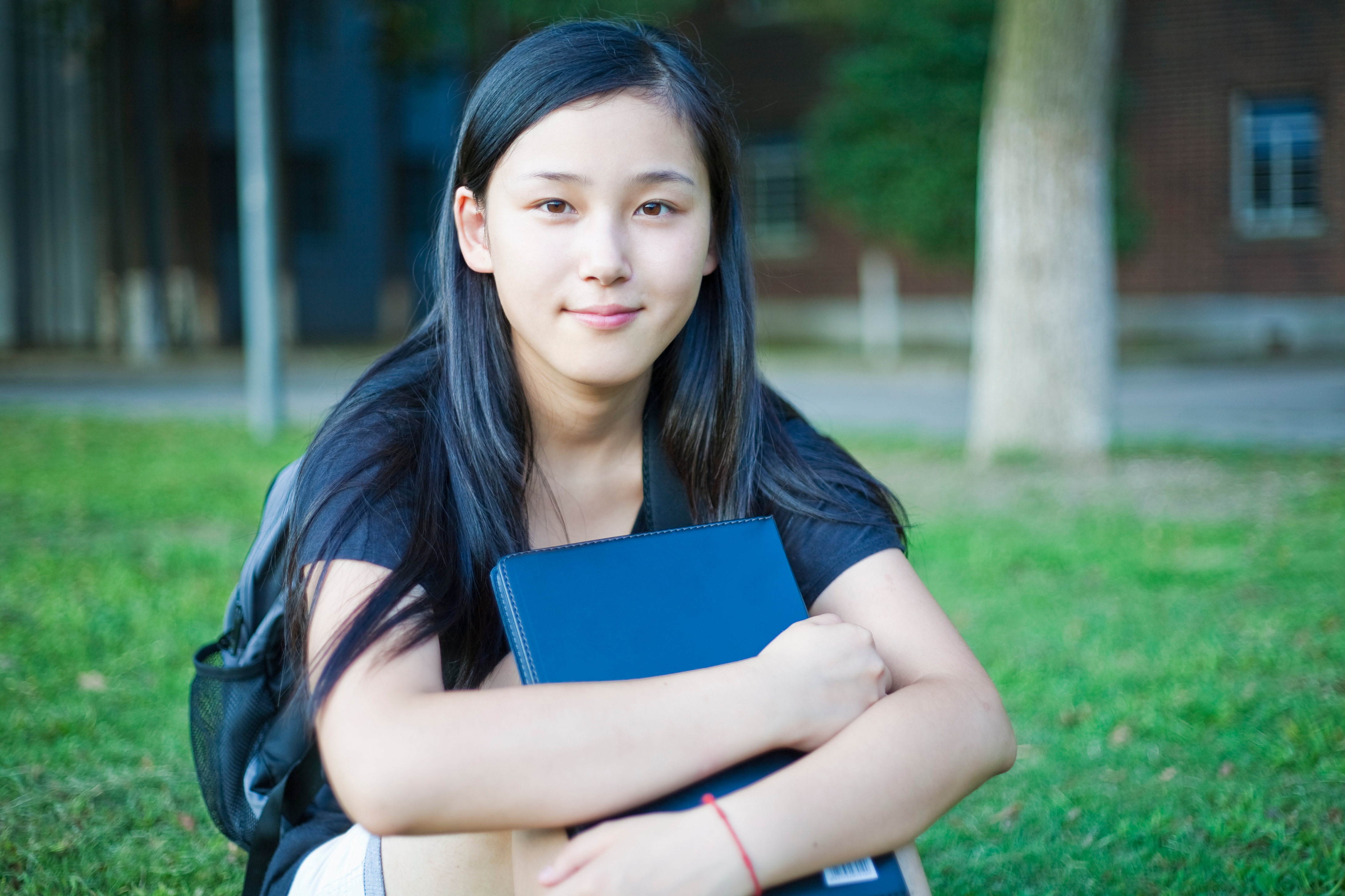 Asian young teen with a warm smile looking straight ahead at school area