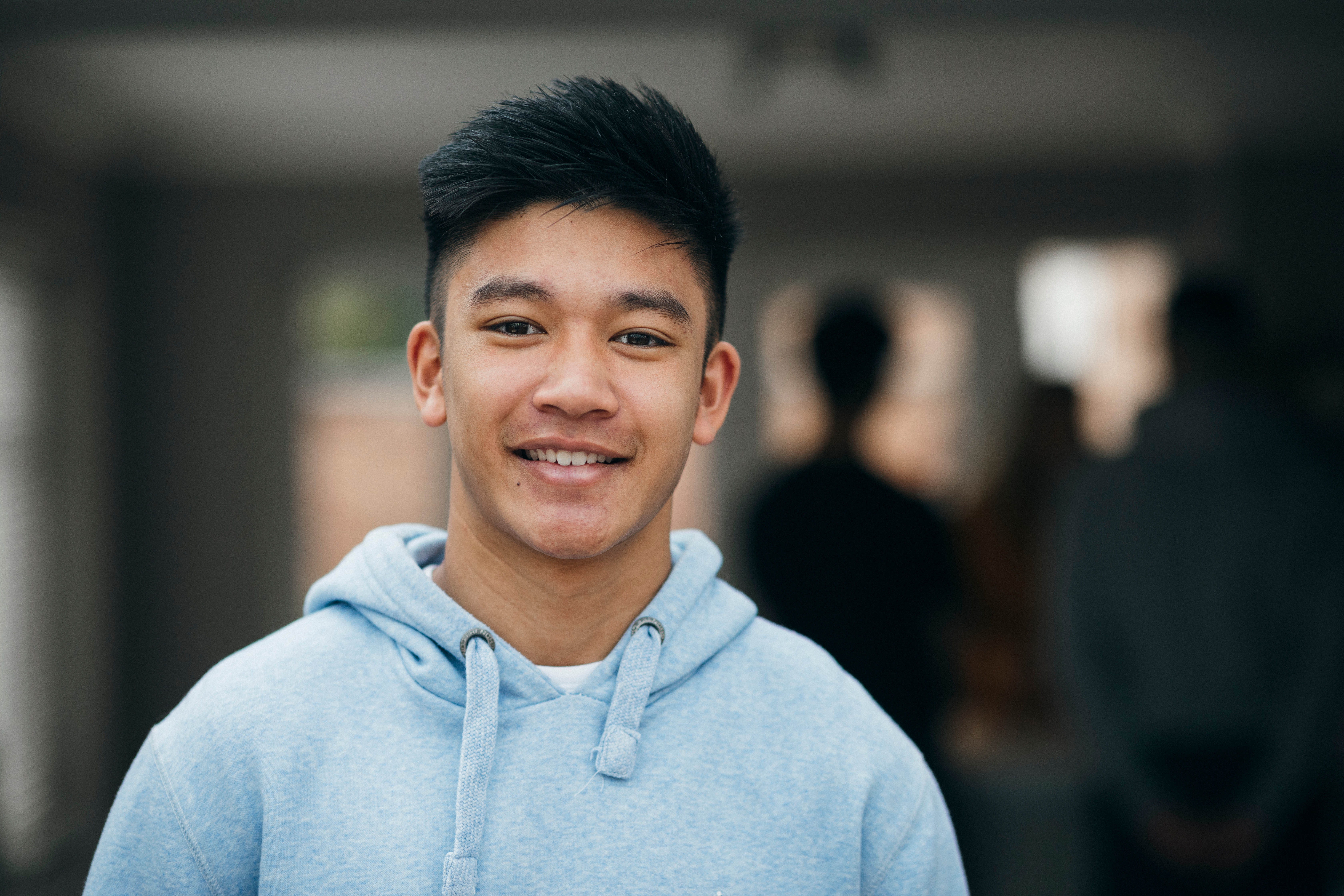 A teen boy smiling  in front of the camera at the school area