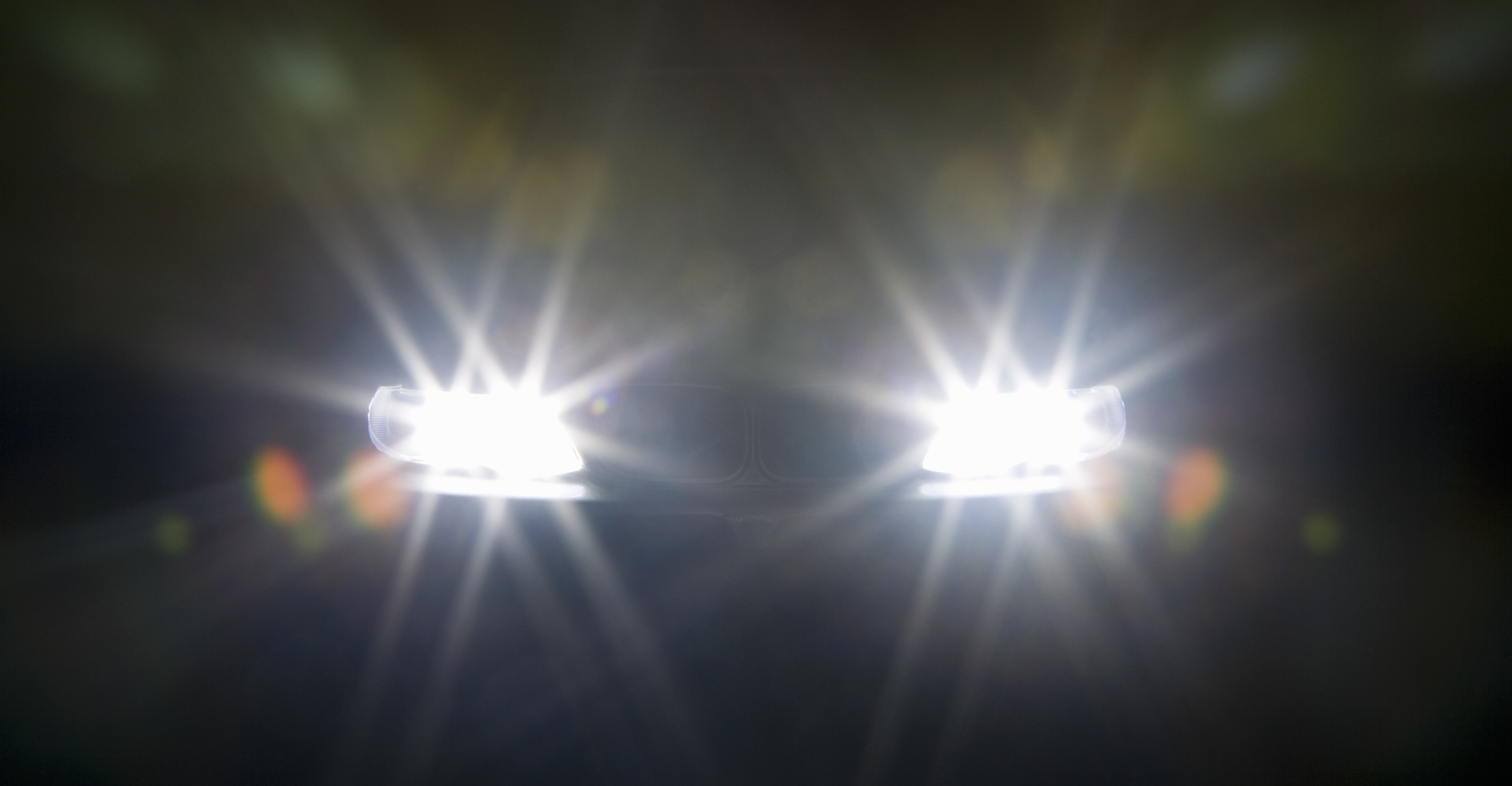 Faróis à noite que mostram halos e raios de luz Faróis à noite que mostram halos e raios de luz