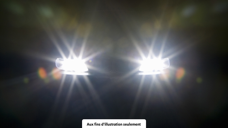 Une photo sombre avec seulement des phares visibles, avec des traînées de lumière en émanant