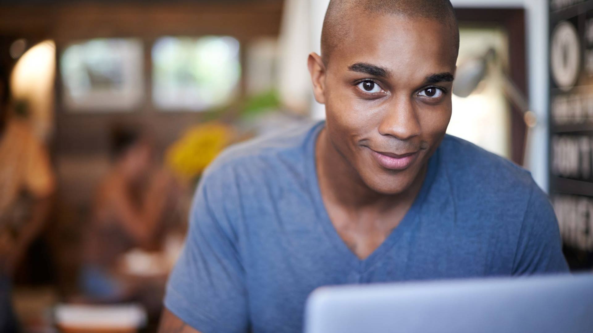 Um homem negro trabalhando em um laptop em um espaço de trabalho compartilhado 