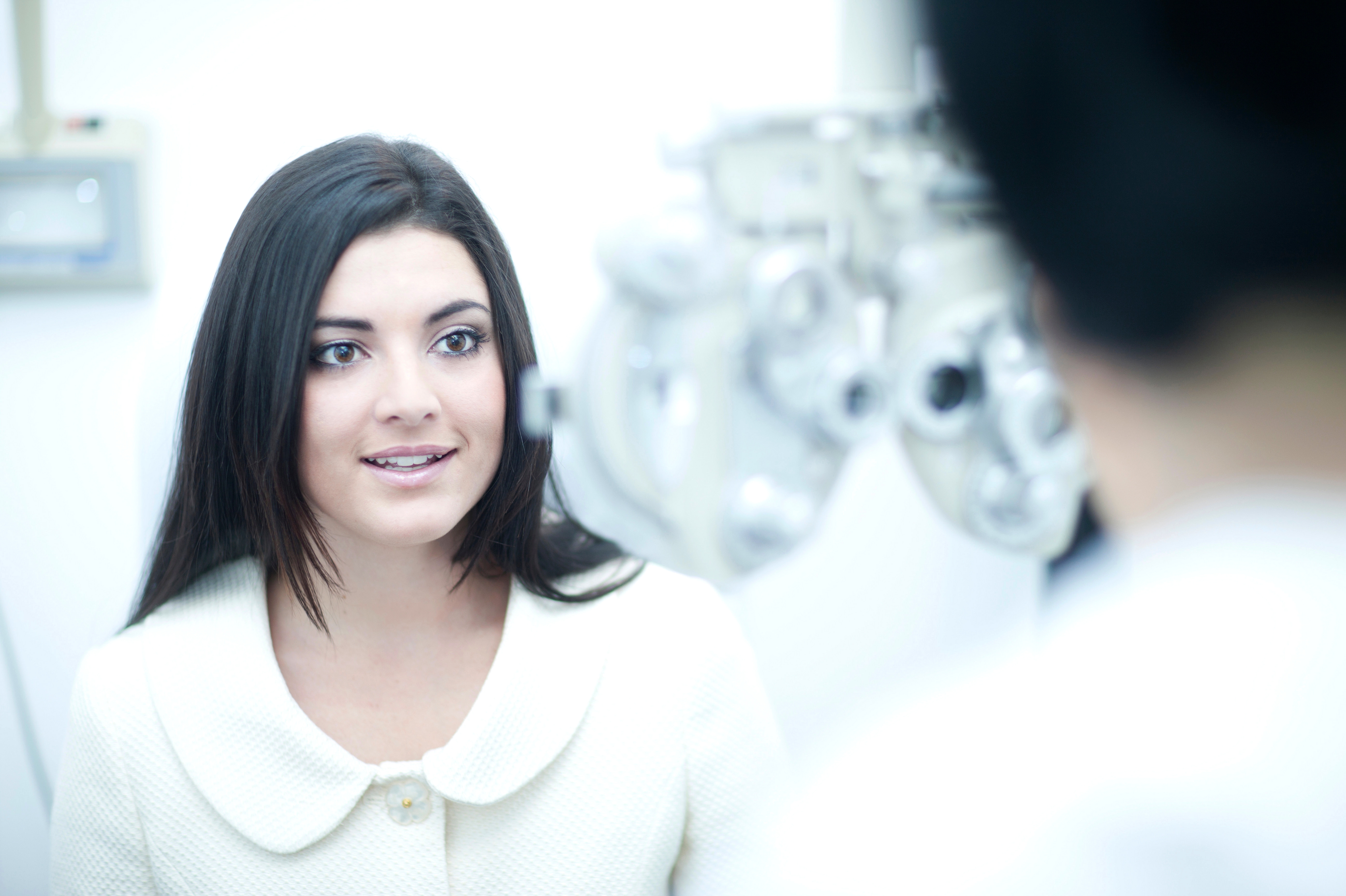 An eye doctor using a phoropter to measure refractive errors.