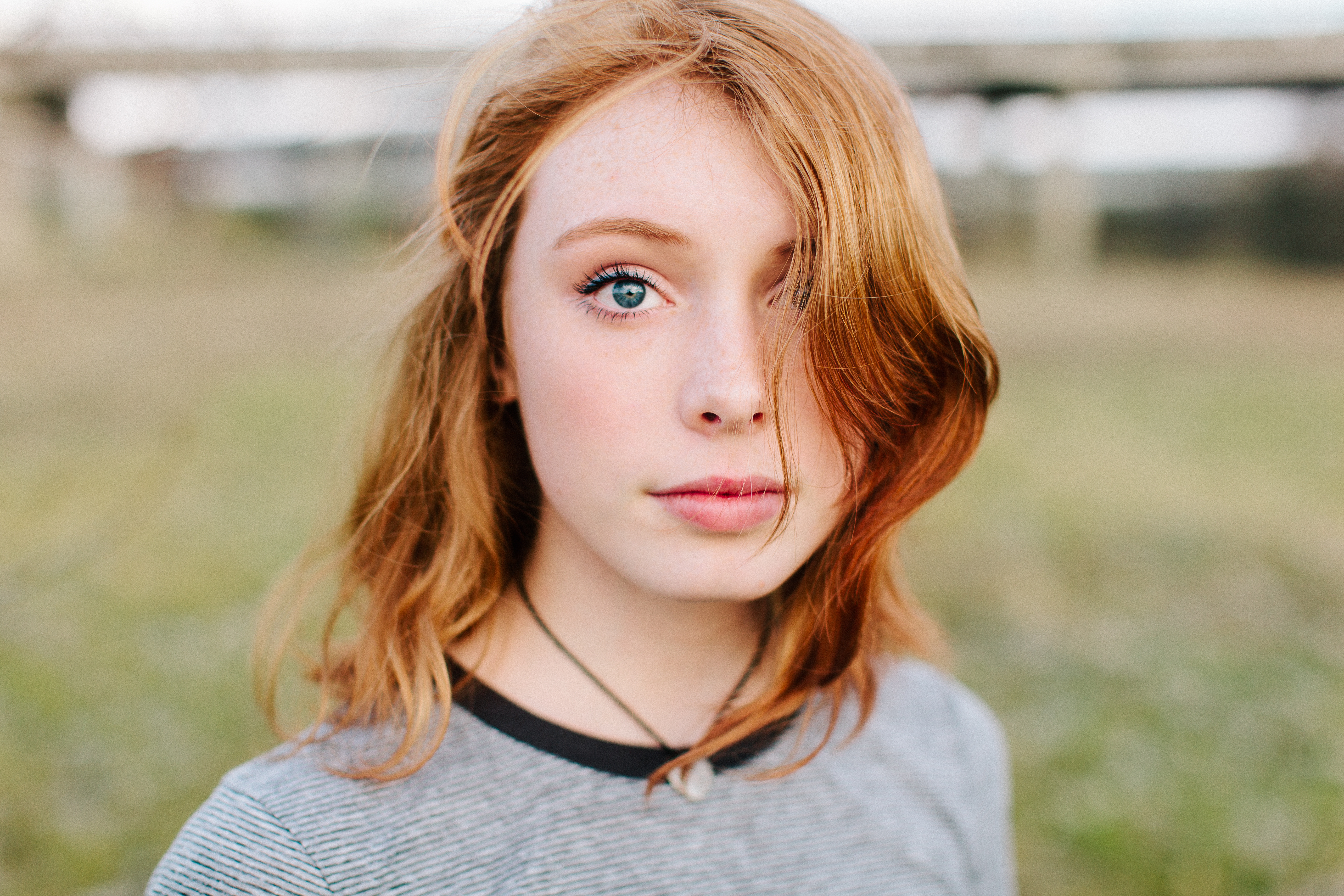 Adolescente aux cheveux roux éclatants et ondulés, vêtue d'un t-shirt gris décontracté