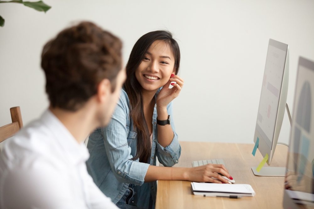 Two young adult having a conversation in a working room setting.