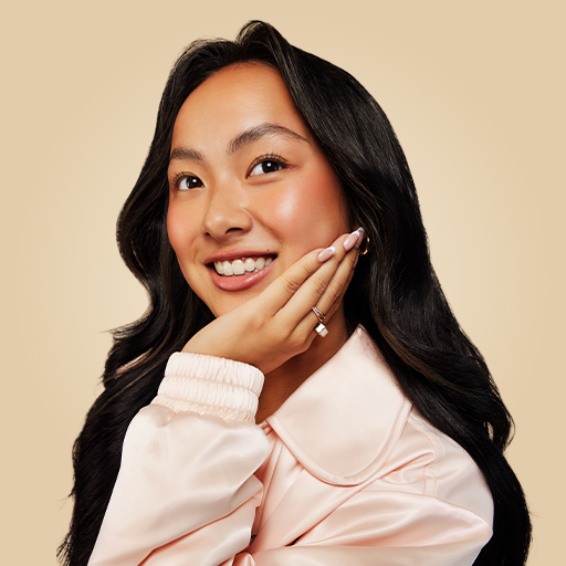 Mujer asiática joven con cabello largo inclinándose hacia un lado y sonriendo Mujer asiática joven con cabello largo inclinándose hacia un lado y sonriendo