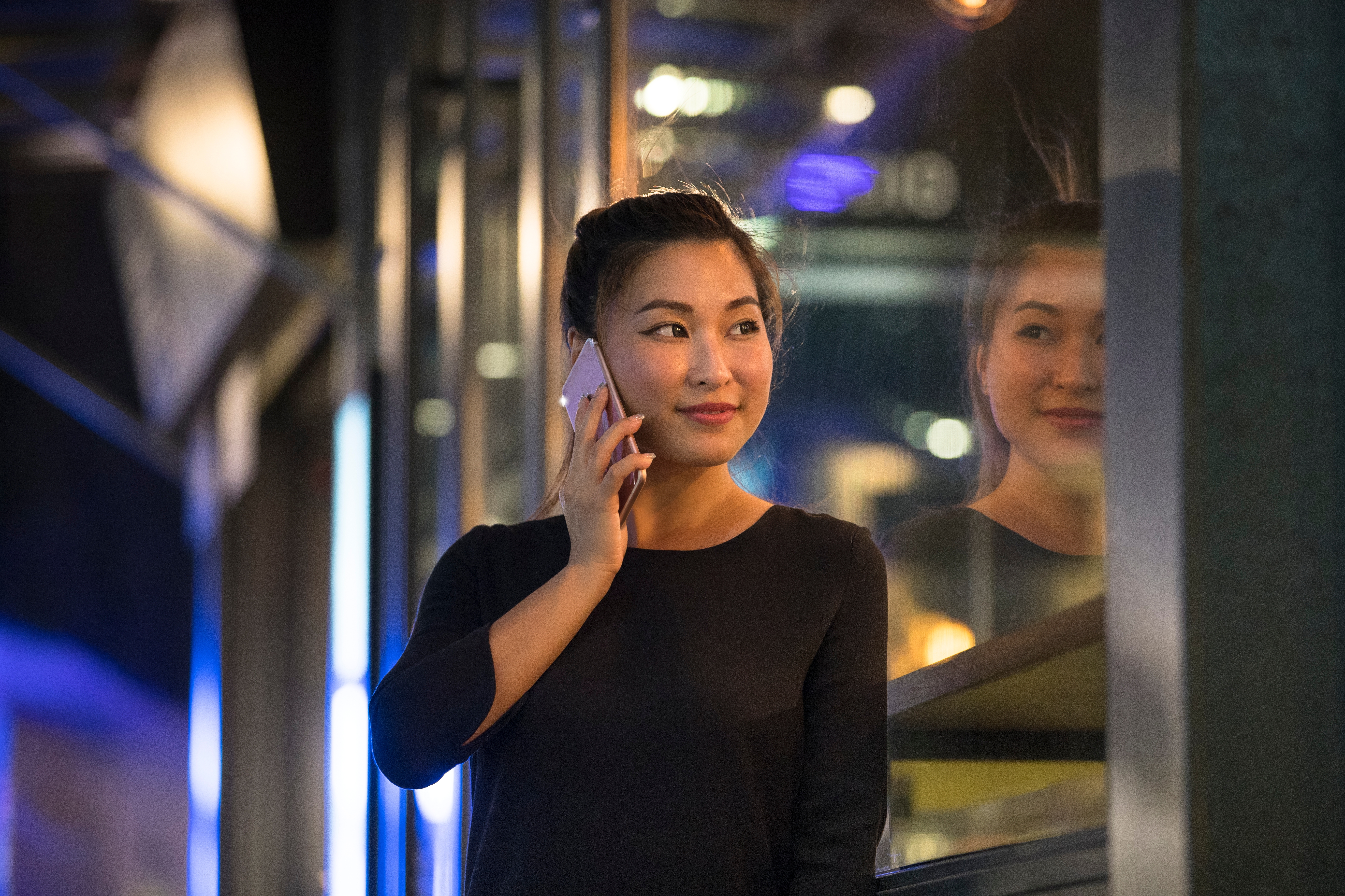 A woman talking on the phone and looking at the window with a smile 