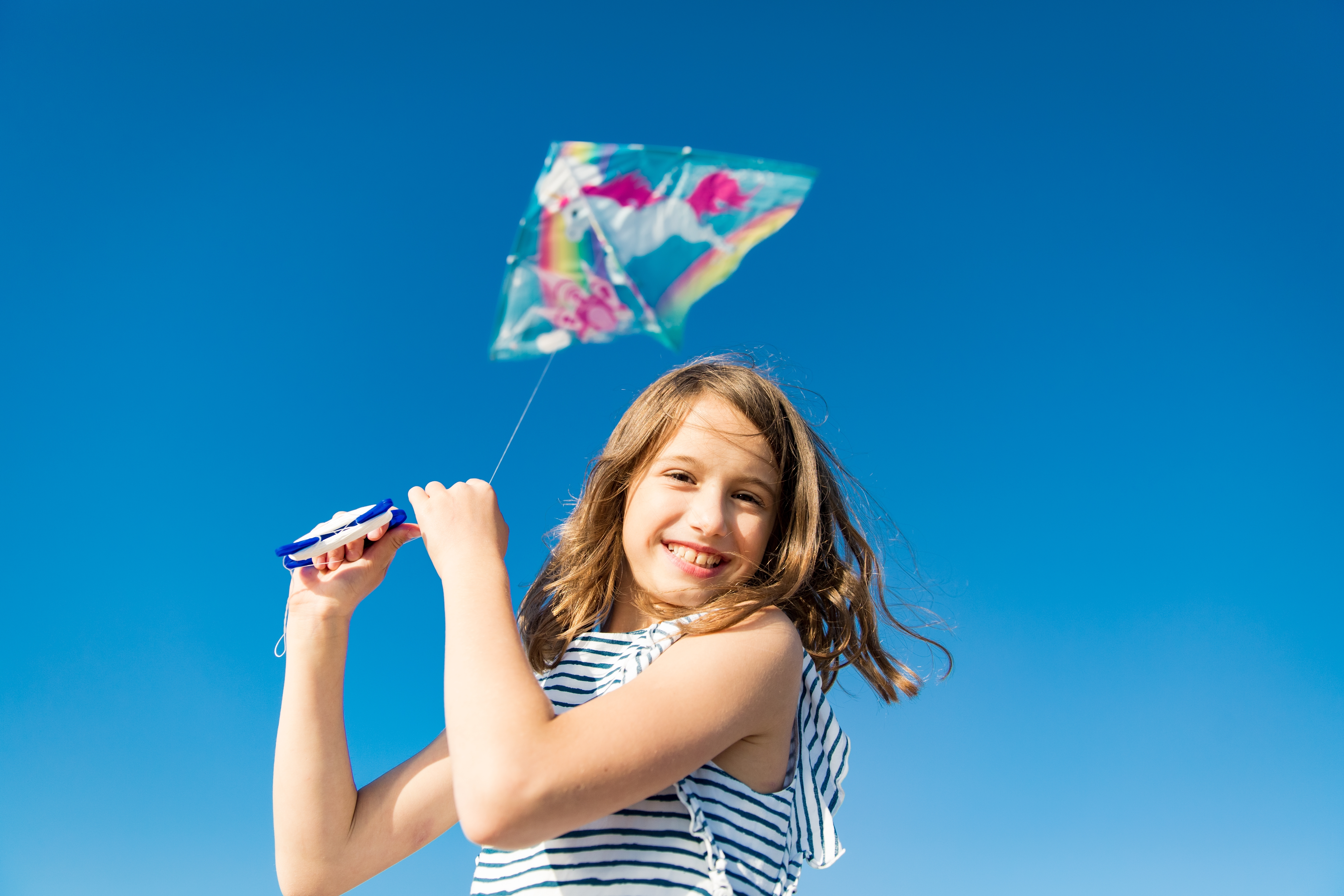 Девочка запускает воздушного змея и улыбаетсяа