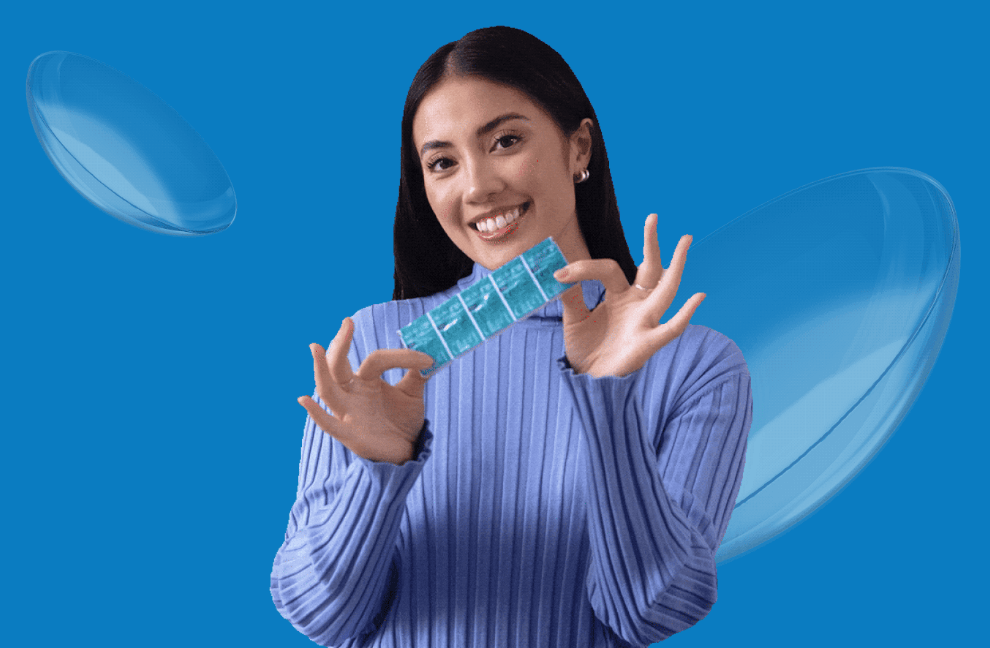 A young woman with dark hair holds a package of contact lenses with floating lenses in the background