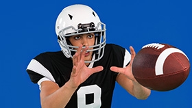 Bryan, a football player and wearer of ACUVUE Contact Lenses catches a football.