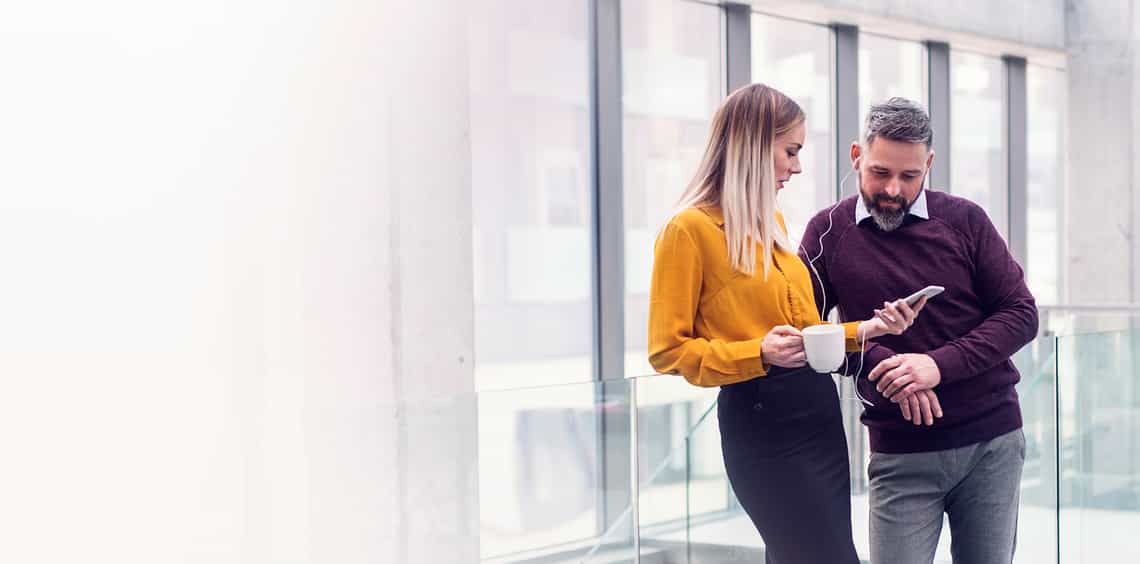 attractive male and female sales professionals looking on a smart phone to review an account plan they learned how to create in richardson's prosperous account strategy training program