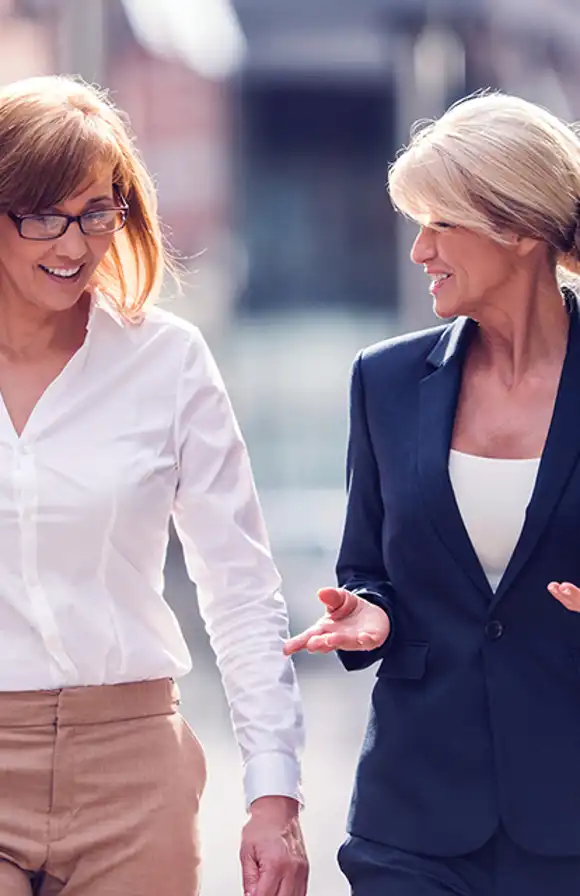a female sales manager provides coaching and feedback to her female seller after a sales call in the field.