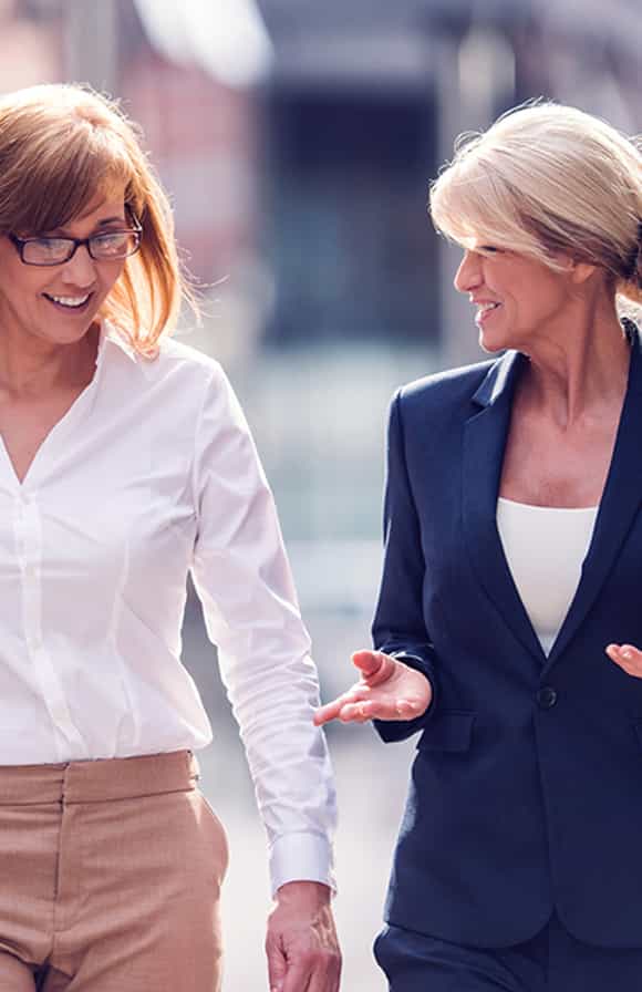 a female sales manager provides coaching and feedback to her female seller after a sales call in the field.