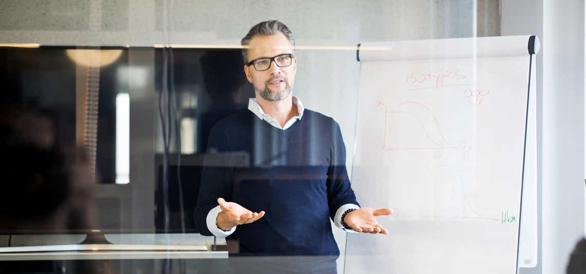 revenue operations leader hosting a team meeting in front of a white board, talking about organizing the revops team
