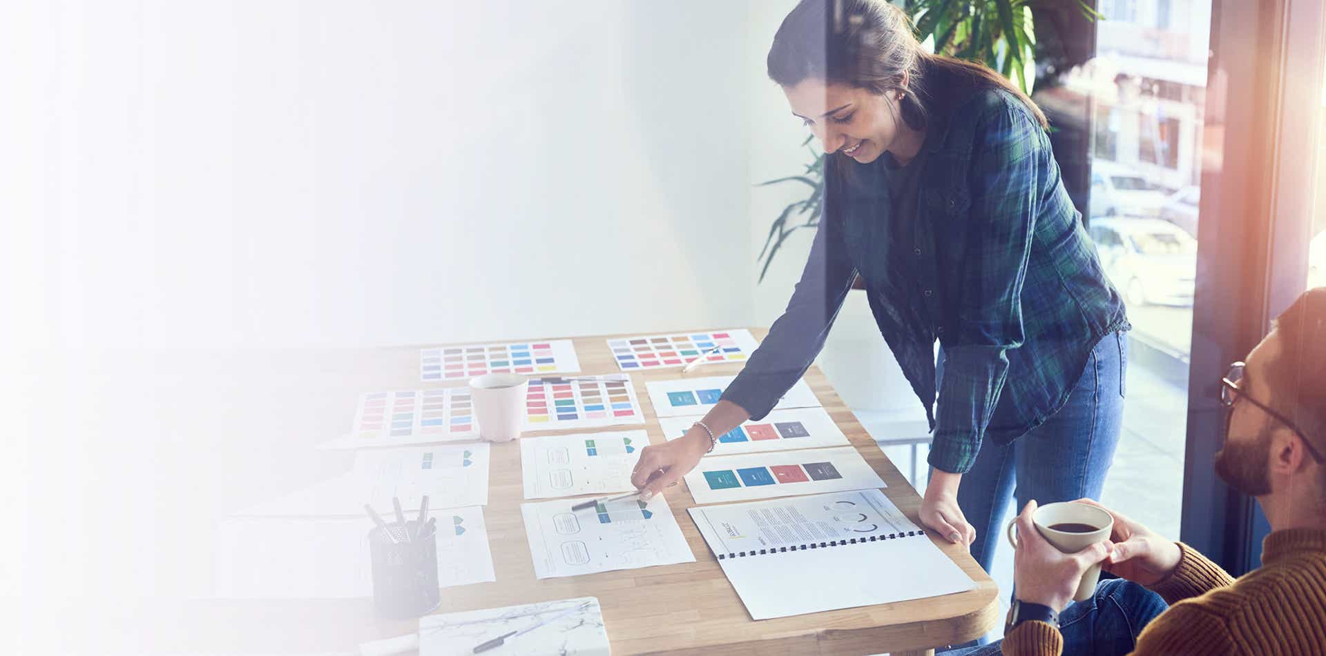 woman leaning over a desk with many papers designing a custom sales training program