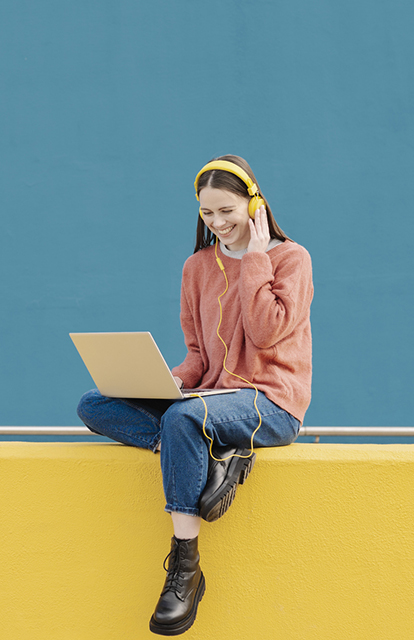 young woman against a bright background on a laptop with headphones on - reading richardson's most recent social media posts
