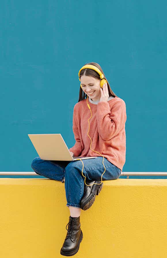 young woman against a bright background on a laptop with headphones on - reading richardson's most recent social media posts