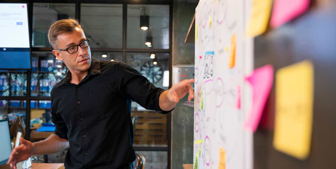 a professional man standing at a whiteboard determining what sales methodology is right for his team.