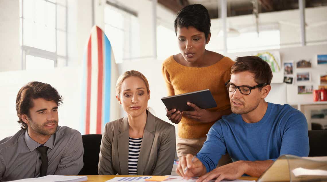 a sales enablement team huddled around a conference exploring a report measuring the performance of their efforts