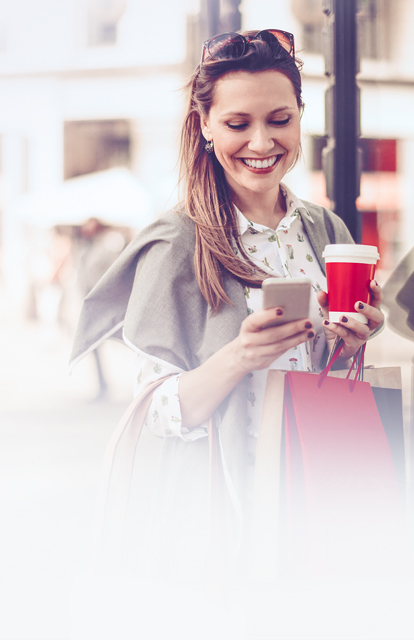 young female sales professional using her cell phone on a city street to complete a simple training reinforcement exercise on Richardson's QuickCheck solution.